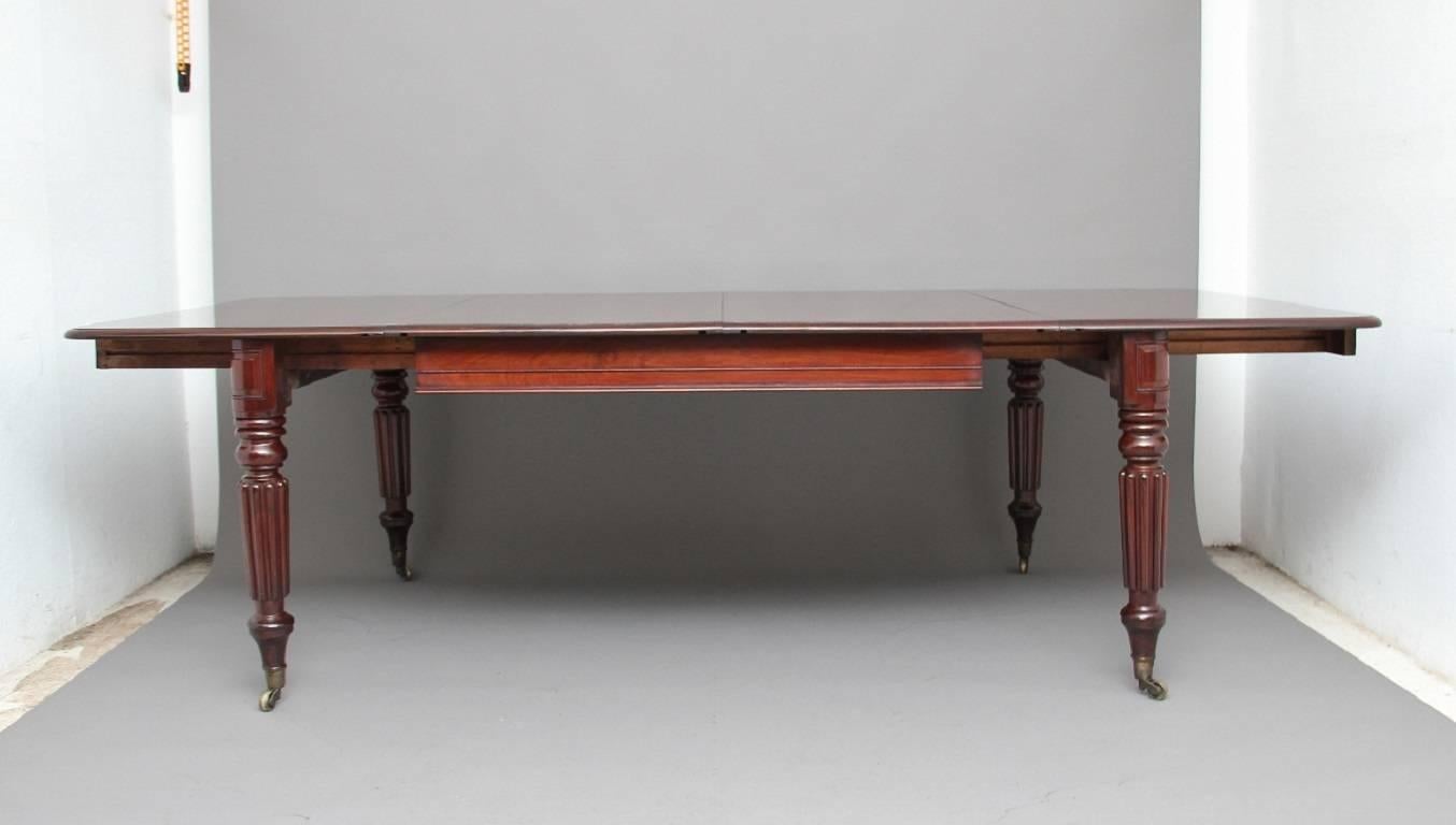 19th century mahogany two-leaf dining table in excellent condition, the lovely solid curl mahogany top with a thumb moulded edge, supported on turned and reeded legs terminating with brass cap castors, circa 1830.