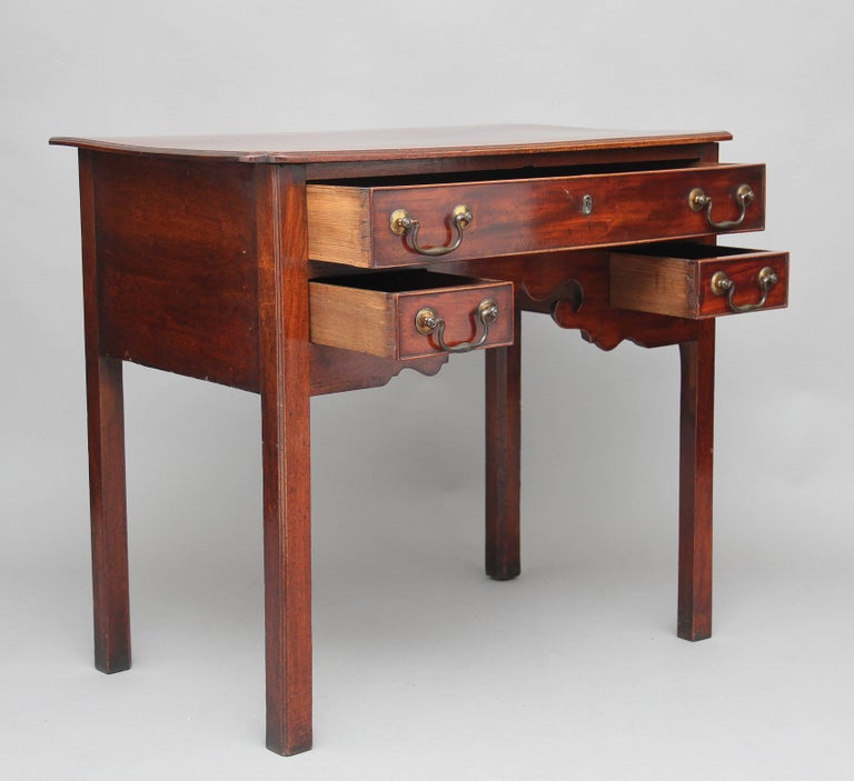 18th century mahogany lowboy, the rectangular moulded edge top having inverted corners at the front, with three oak lined drawers below, a combination of one long drawer over two short drawers, all with original brass swan neck handles, with a