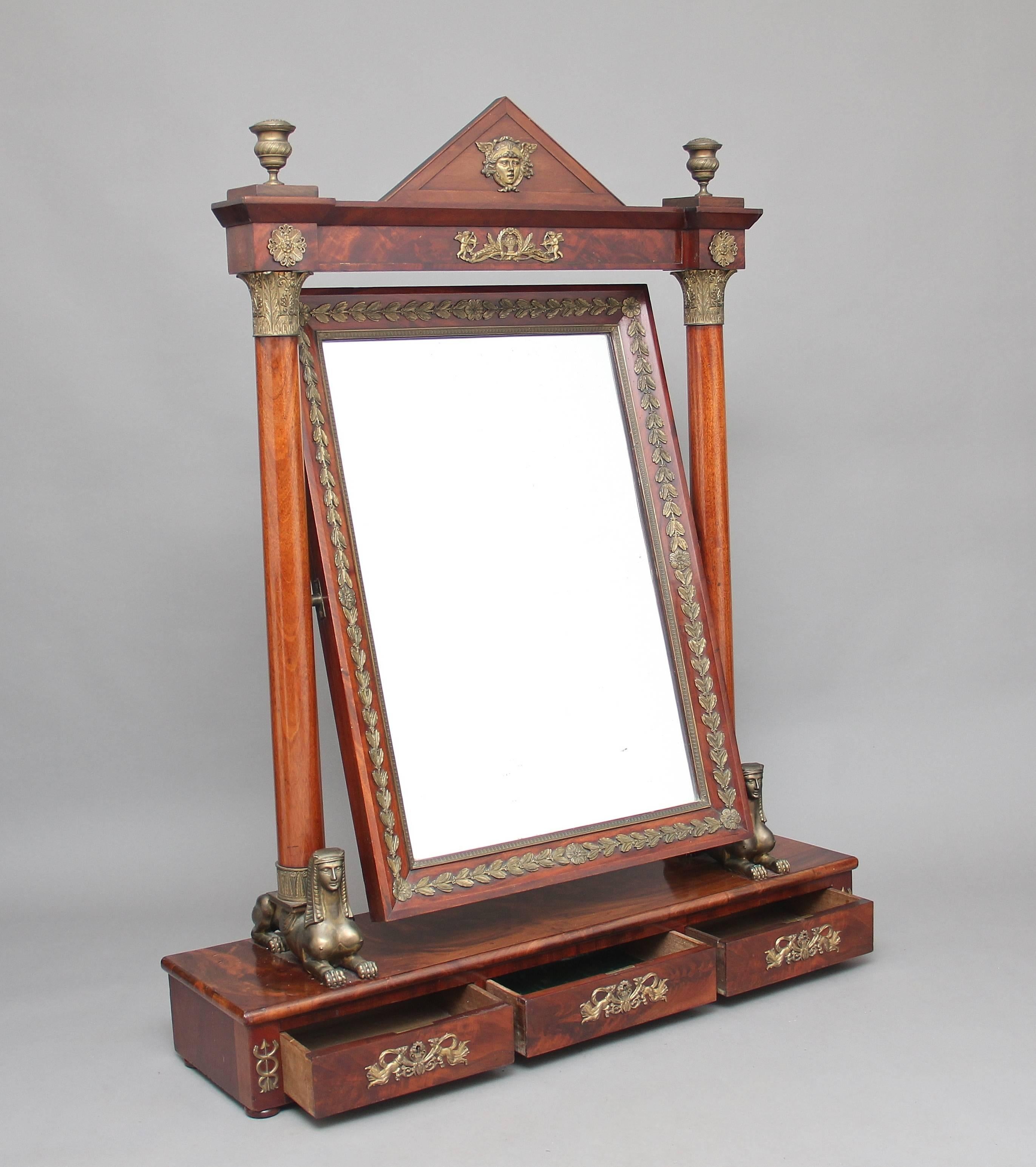 A very impressive large 19th century mahogany and ormolu French Empire dressing mirror with an Egyptian influence, the pyramid shaped top with an ormolu face flanked by ormolu urns, the large swing mirror having ormolu leaf decoration around the