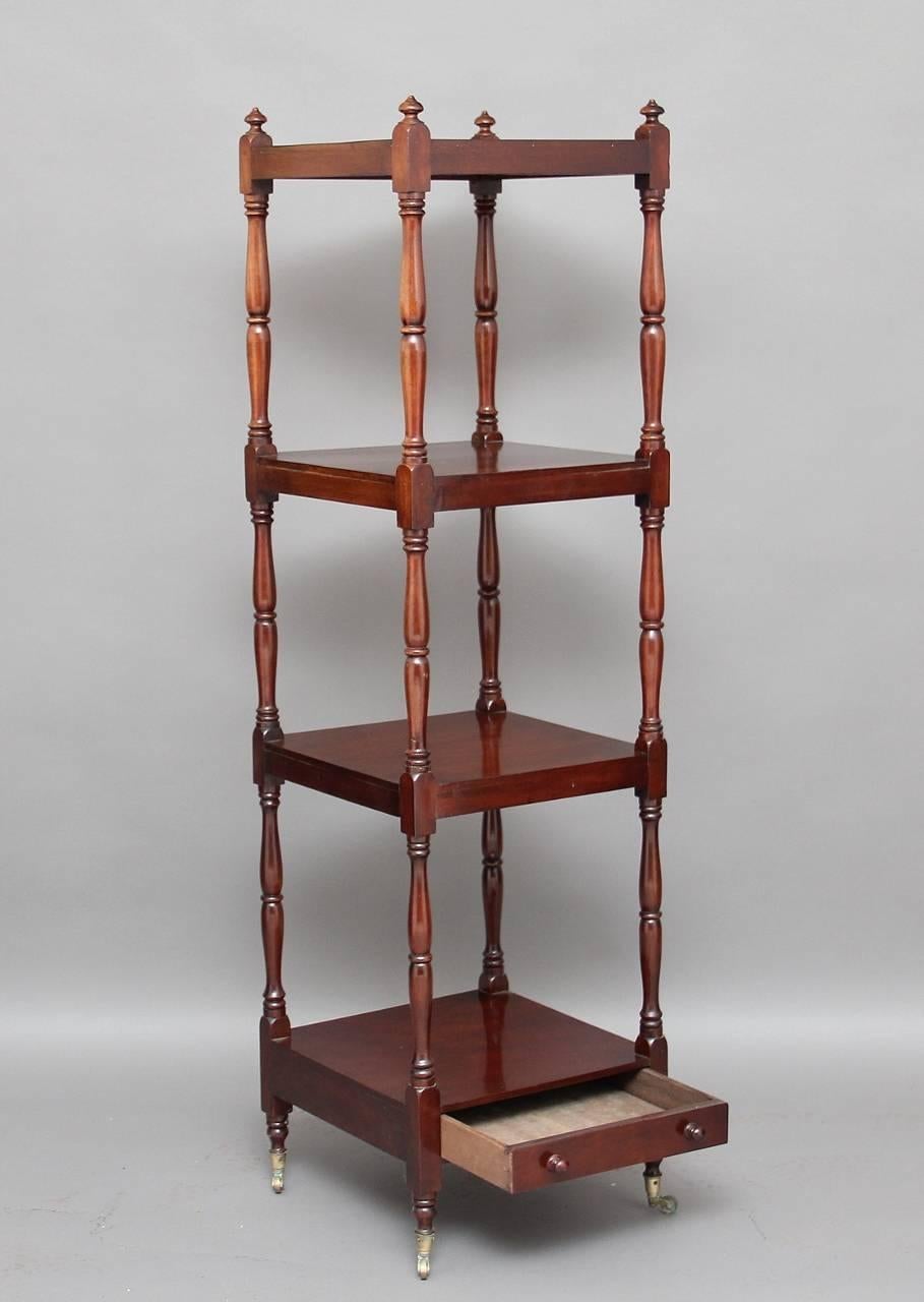 19th century four-tier mahogany whatnot with an oak lined drawer at the bottom with original turned knobs, the structure supported with finely turned columns with the top section having turned finials, standing on brass castors, circa 1850.
 