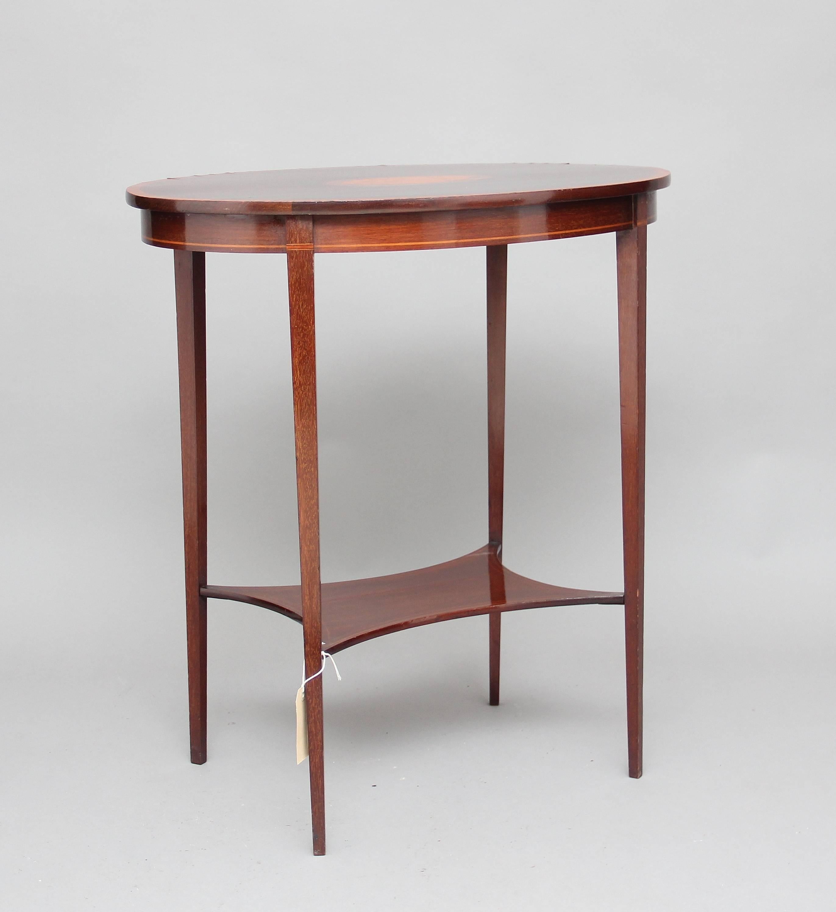 Early 20th century inlaid mahogany occasional table, the oval top having a decorative shell inlay, supported on square tapering legs united by a shaped shelf, circa 1910.