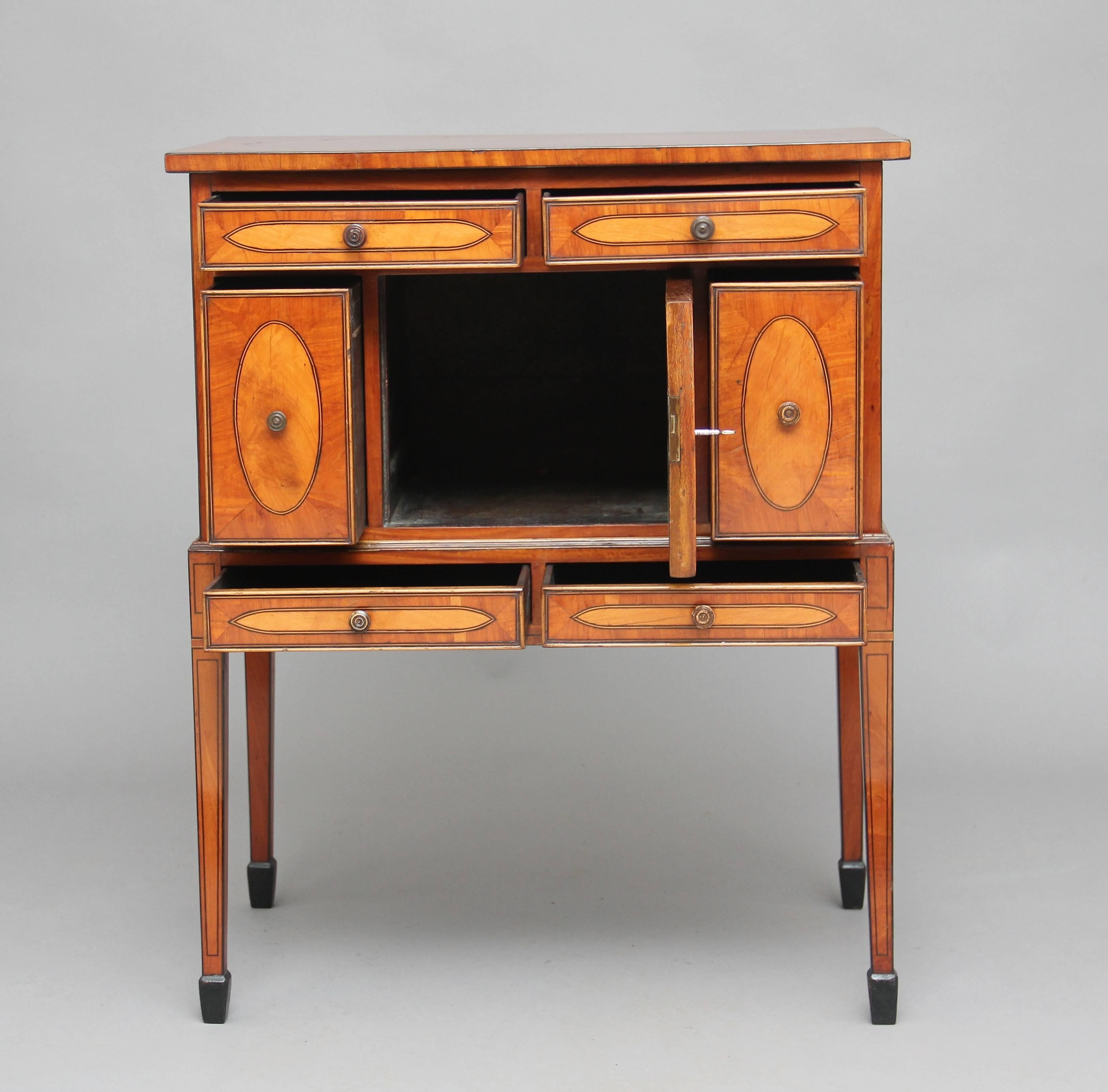A lovely quality early 19th century satinwood cabinet inlaid all over, with oval satinwood panels with ebony and boxwood stringing, the top section with two long drawers above a central cupboard flanked by two deep drawers, standing on a tapered leg