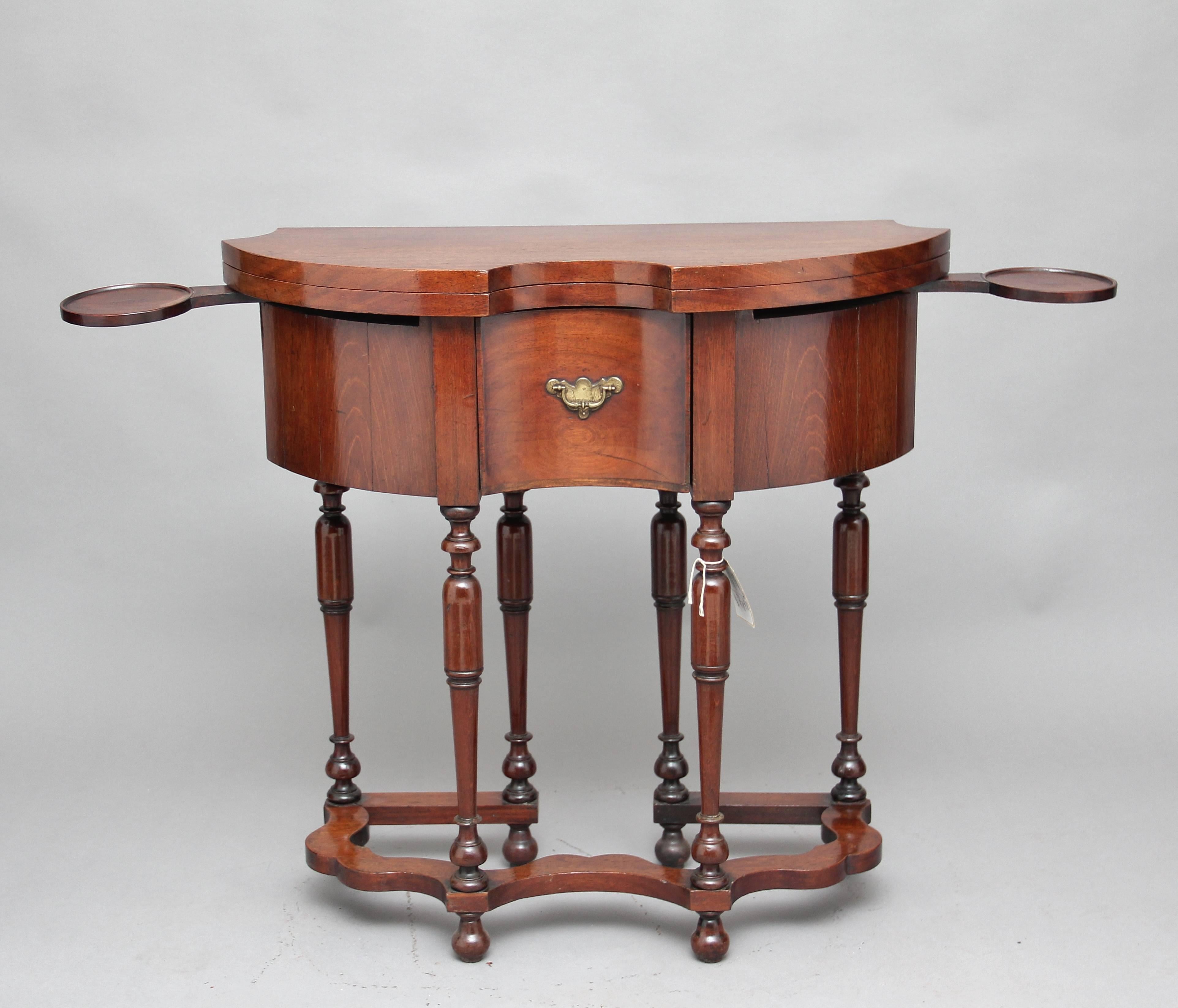 A very rare mid-18th century teak games table, the shaped hinged fold over top above a deep shaped apron with a single oak lined drawer in the centre with original brass plate handle, supported on six elegant turned legs united by a shaped stretcher