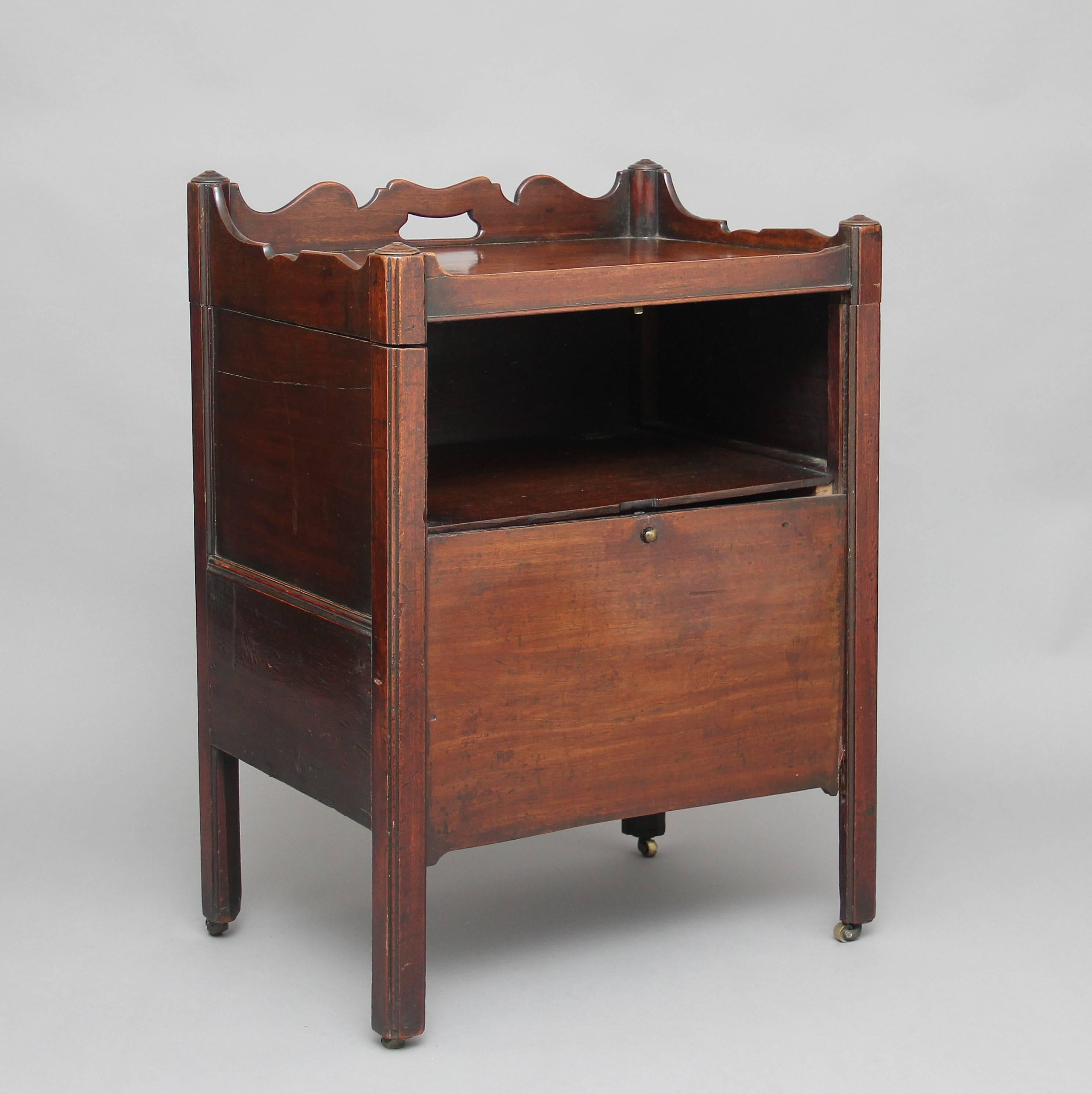Comodino in mogano del XVIII secolo, il piano incernierato e sollevabile ha una galleria sagomata e forata, la parte anteriore dell'armadio ha un pannello che scorre verso il basso per rivelare un vano, su gambe quadrate sollevate da rotelle in