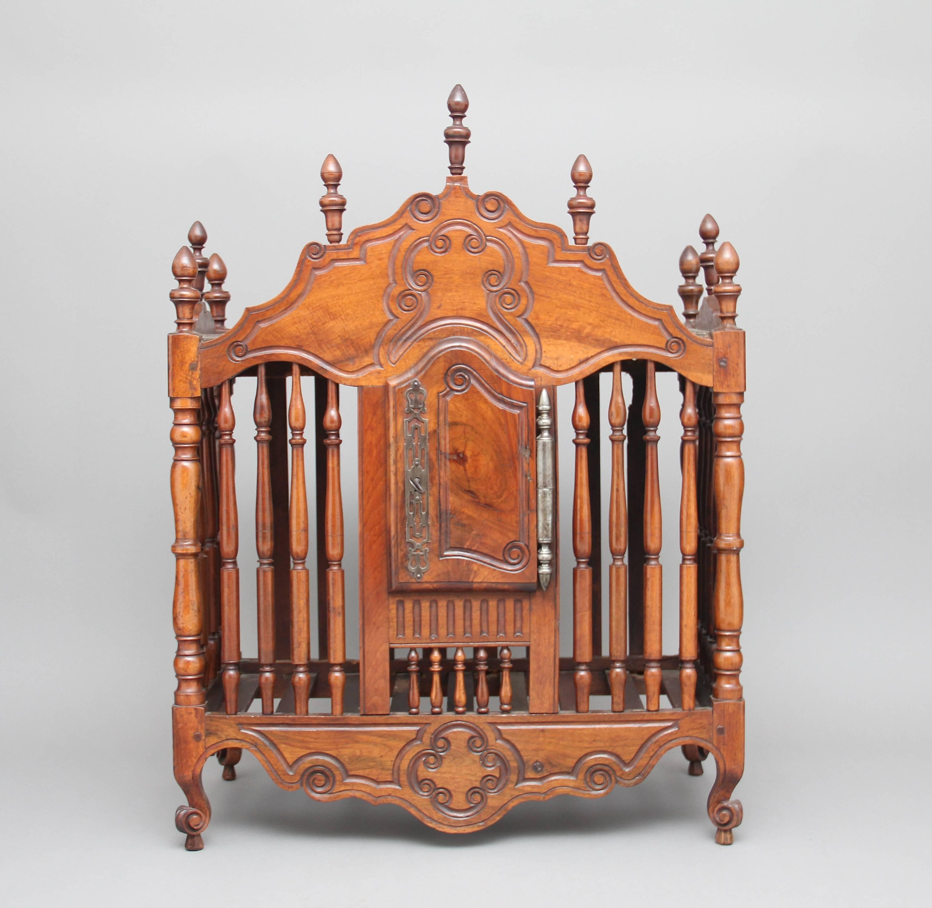 Early 19th century French fruitwood food cupboard, the carved and shaped top decorated with turned finials, the main section having spindles at the sides and front with a door at the centre with a pierced steel escutcheon and heavy hinge, with a