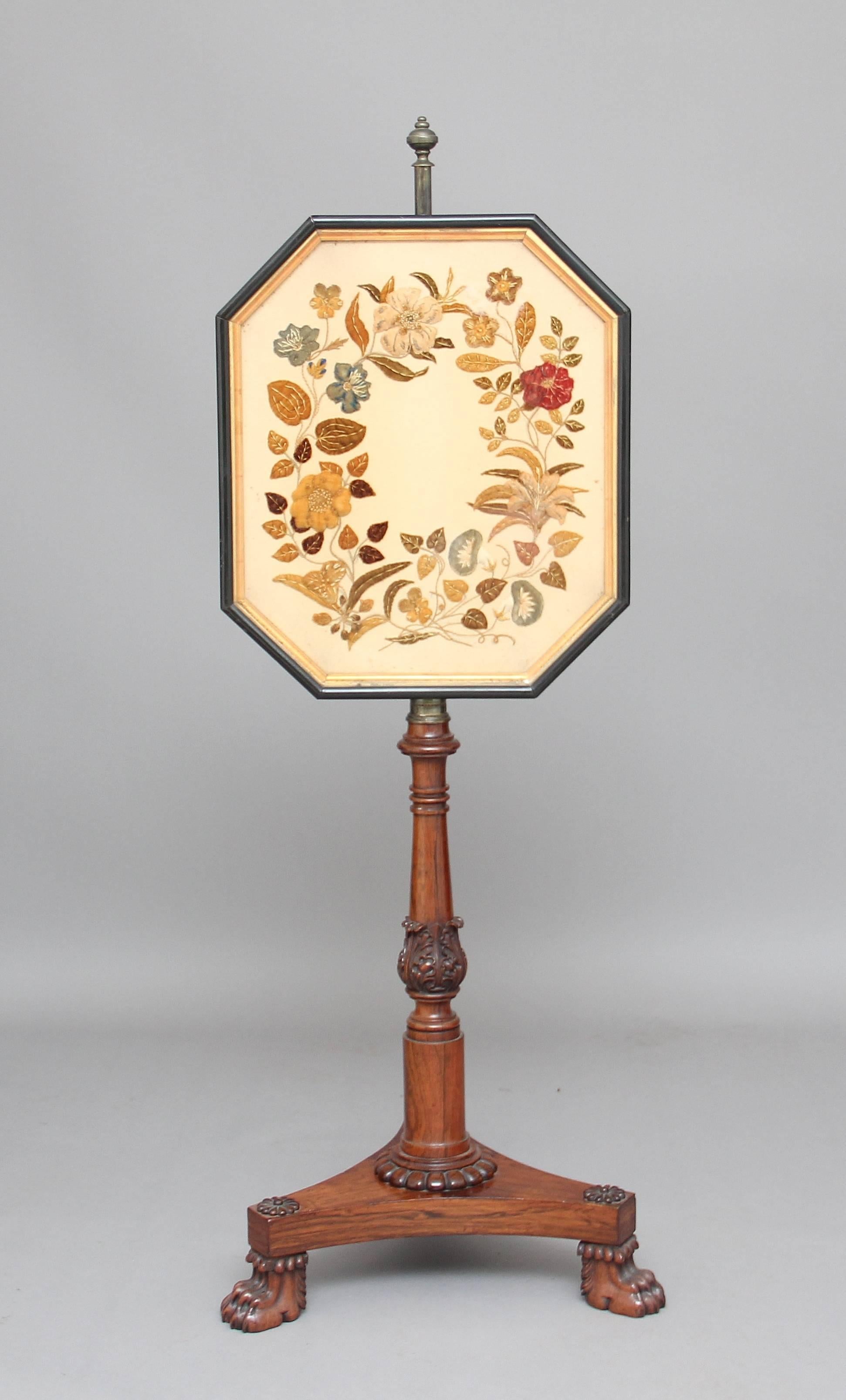 19th century rosewood fire screen, the shaped screen with the needlepoint depicting a lovely floral scene, supported on a turned and carved column which leads down to a tri form base decorated with carved patraes, standing on claw feet, circa