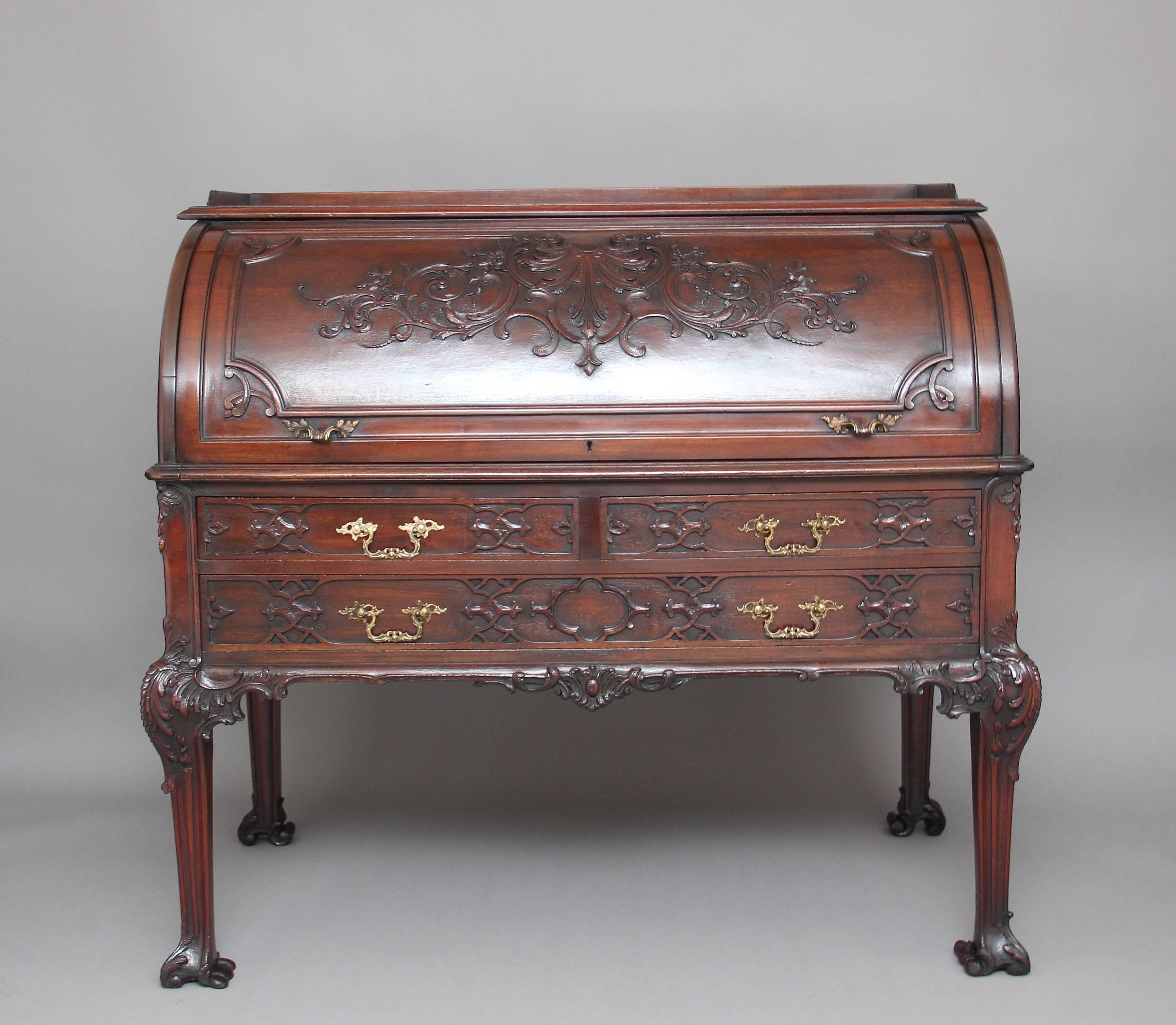 Early 20th century mahogany cylinder desk in the Chinese Chippendale style, the top has a gallery running along the sides and back, with the cylinder below is panelled and moulded with carving at the centre opening to reveal a leather writing