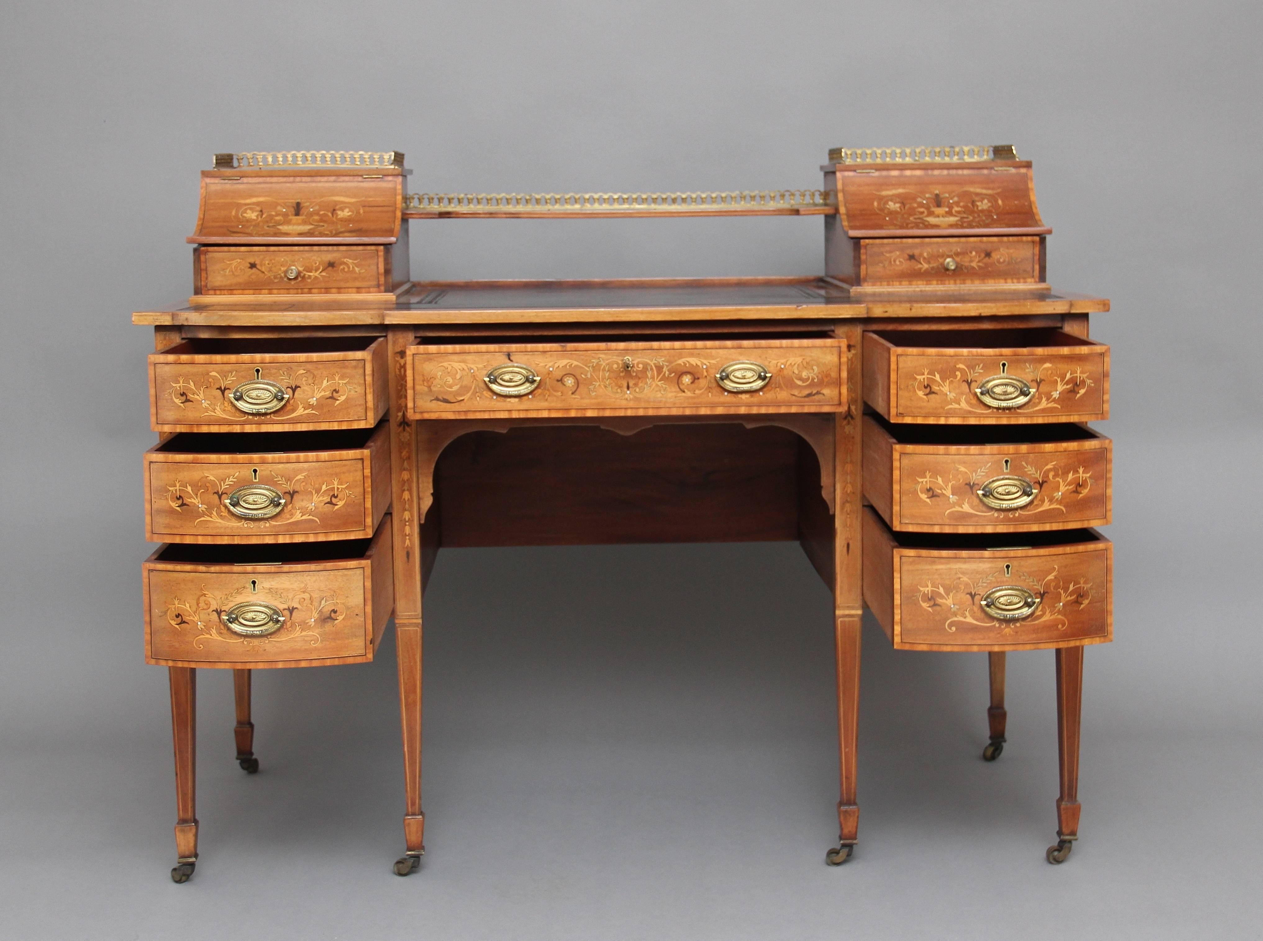 Early 20th century mahogany inlaid desk, the top having a shelf flanked either side by concave hinged stationary compartments beautifully inlaid with scrolling flowers and urns, each with a drawer, one fitted with a pair of inkwells, the other with