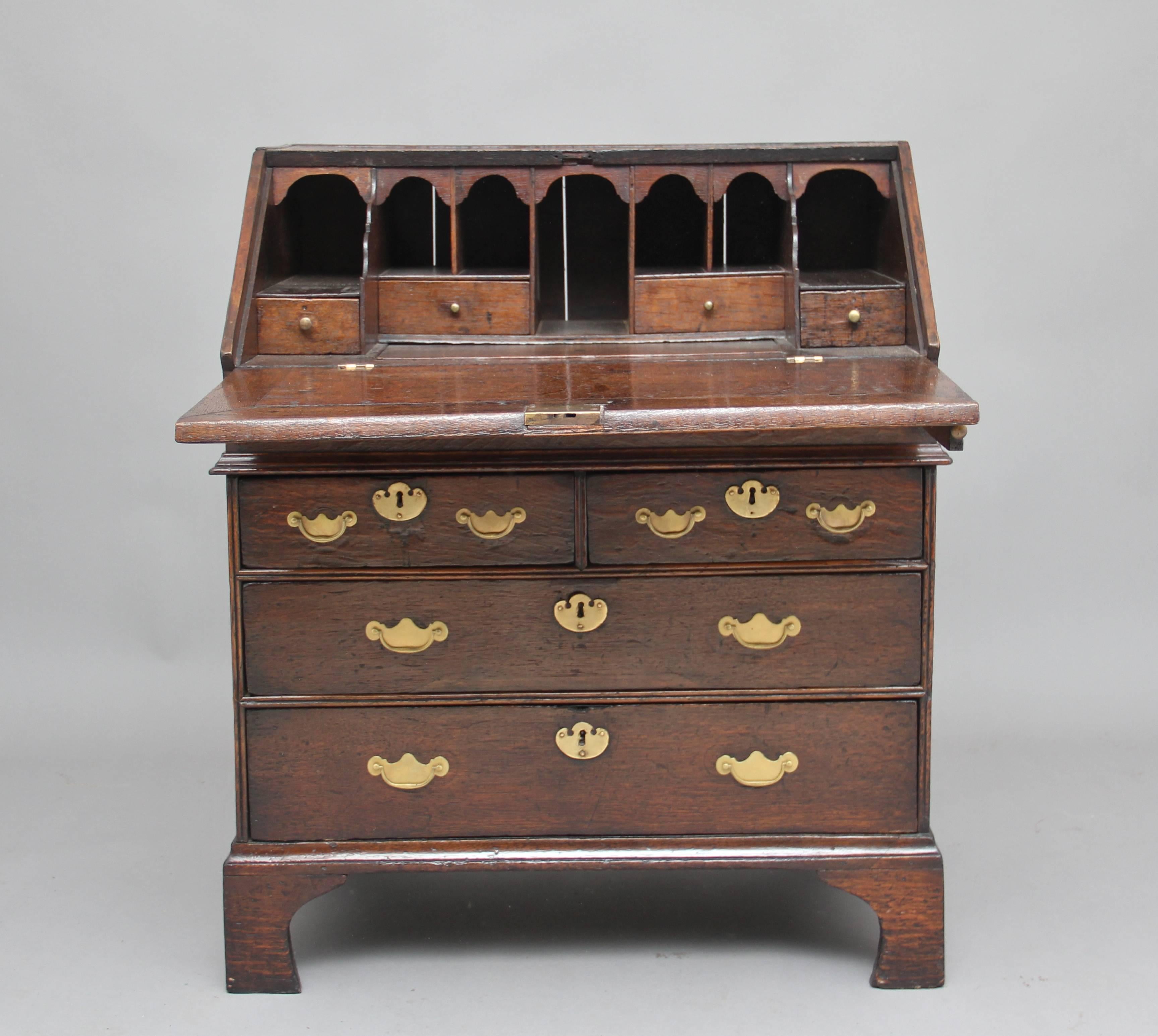 Early 18th Century oak bureau, the fall opening to reveal a lovely fitted interior with various drawers, compartments and a well, the bureau having two short over two long oak lined drawers with brass plate handles and escutcheons, standing on