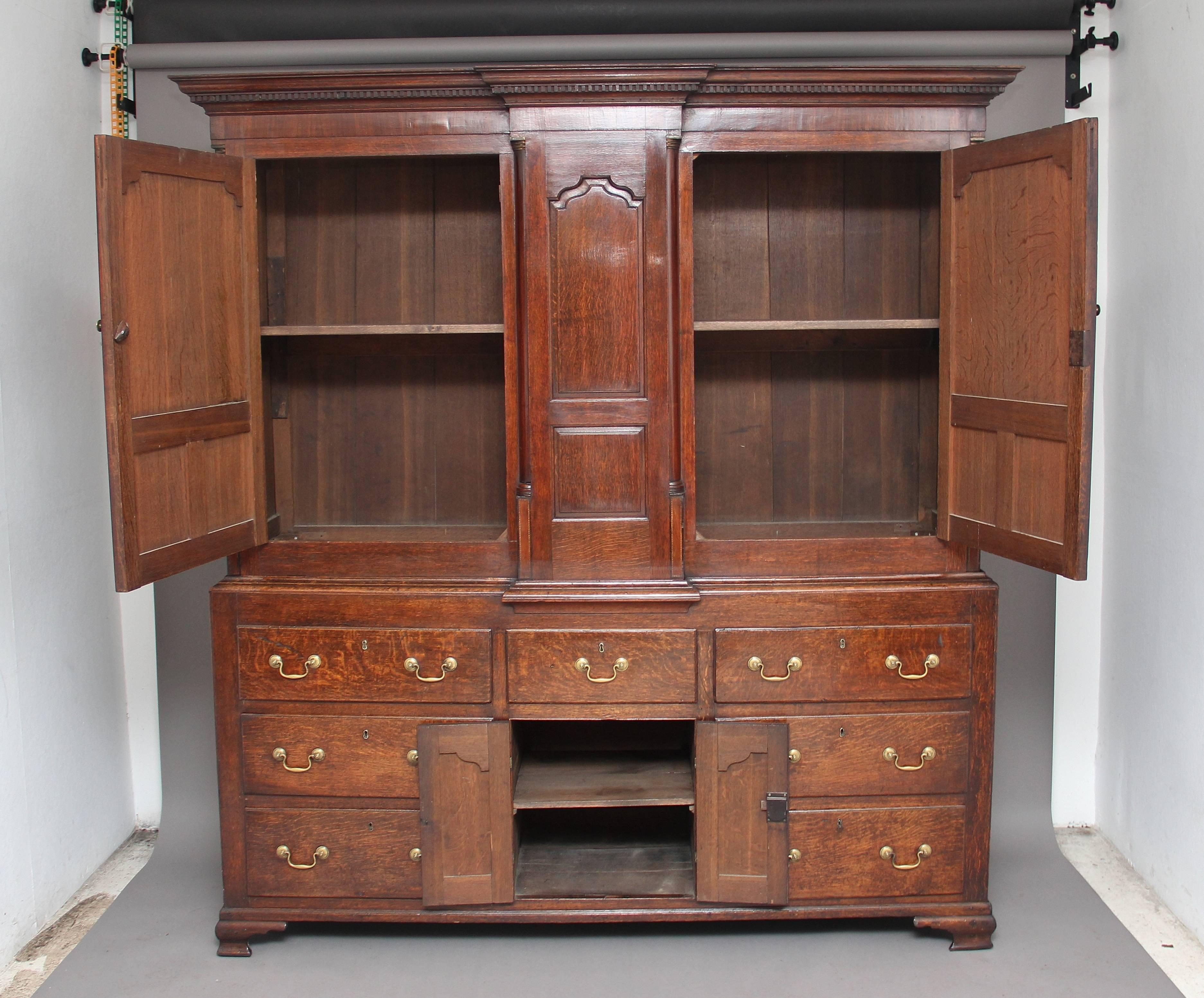18th century oak housekeepers cupboard of wonderful proportions, the cupboard is in two sections, the top section of breakfront from with a door either side of a central panel, the doors and central panel are fielded framed by quarter columns, the