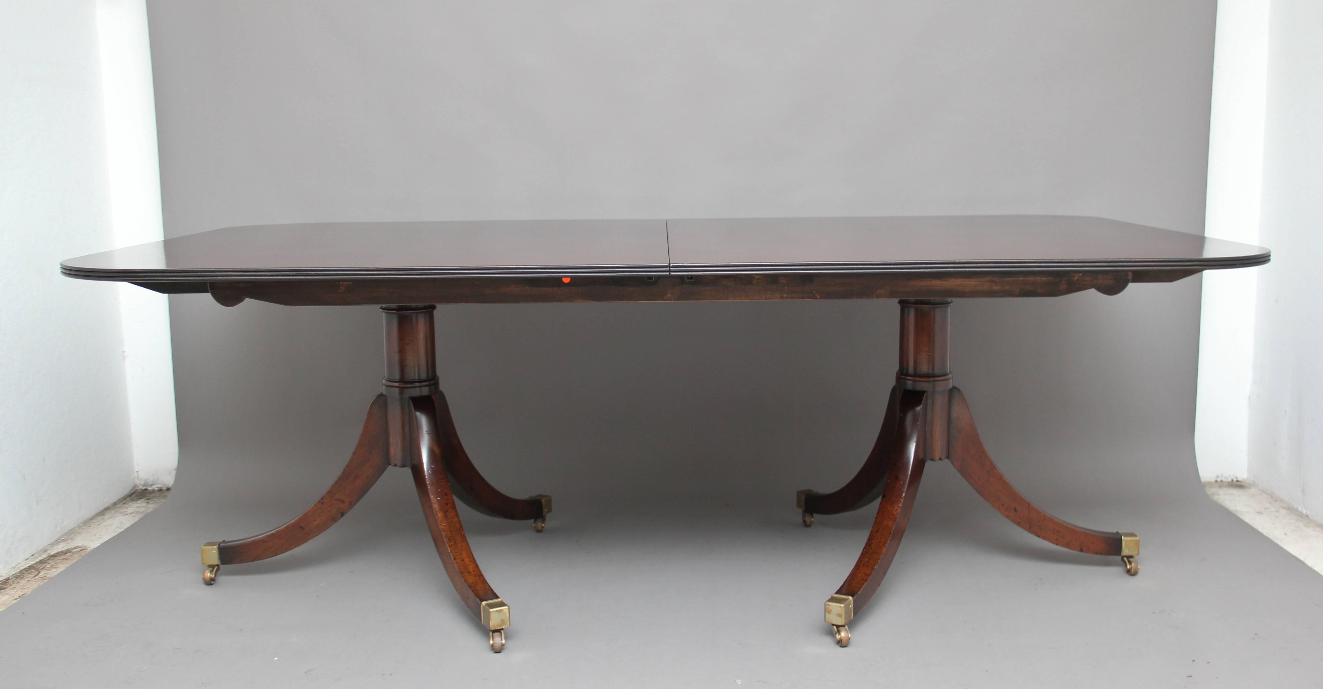 Mid 20th Century mahogany twin pedestal dining table incorporating two additional leaves, the rounded rectangular top with a reeded edge, raised on turned columns with three splay legs with brass caps and castors.  Circa 1950.