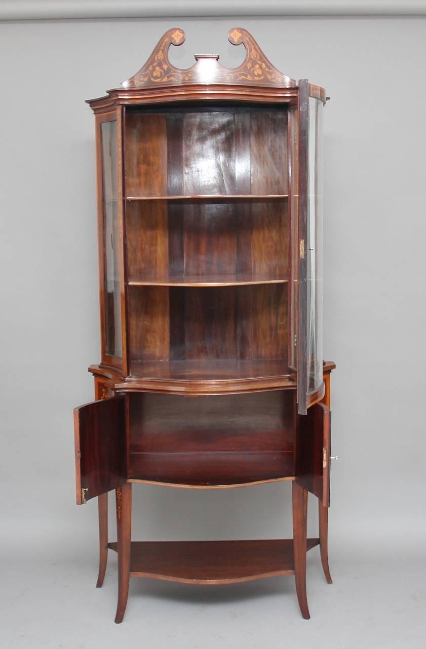 19th century mahogany Sheraton revival inlaid display cabinet by Edwards & Roberts profusely inlaid all over with floral marquetry, the inlaid broken arch pediment sitting in a moulded edge frieze, with a serpentine shaped single glazed door below