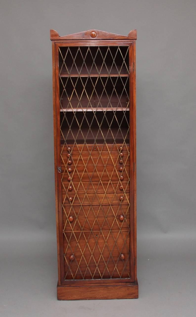 19th century mahogany collectors cabinet, the top having an architectural pediment, the single grill door with original lock and key opening to reveal two shelves at the top and nine graduated drawers below with original mahogany turned knobs, two