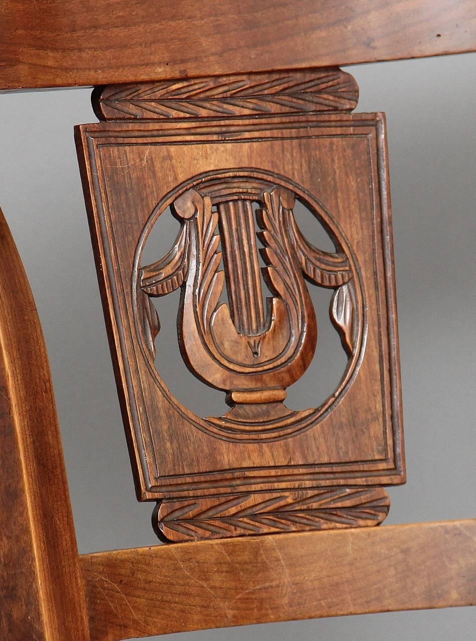 Pair of 19th century French fruitwood chairs with carved decoration in the centre backs, with a rush seat standing on square front legs and swept back legs, circa 1830.