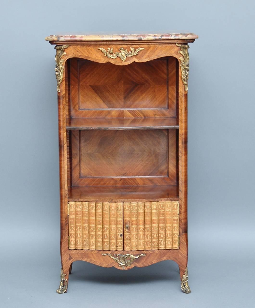 19th century French kingwood bookcase or cabinet with a shaped variegated marble top with a moulded edge, below a nicely shaped frieze along the front and sides, the bookcase is crossbanded all over decorated with lovely quality brass mounts, with a