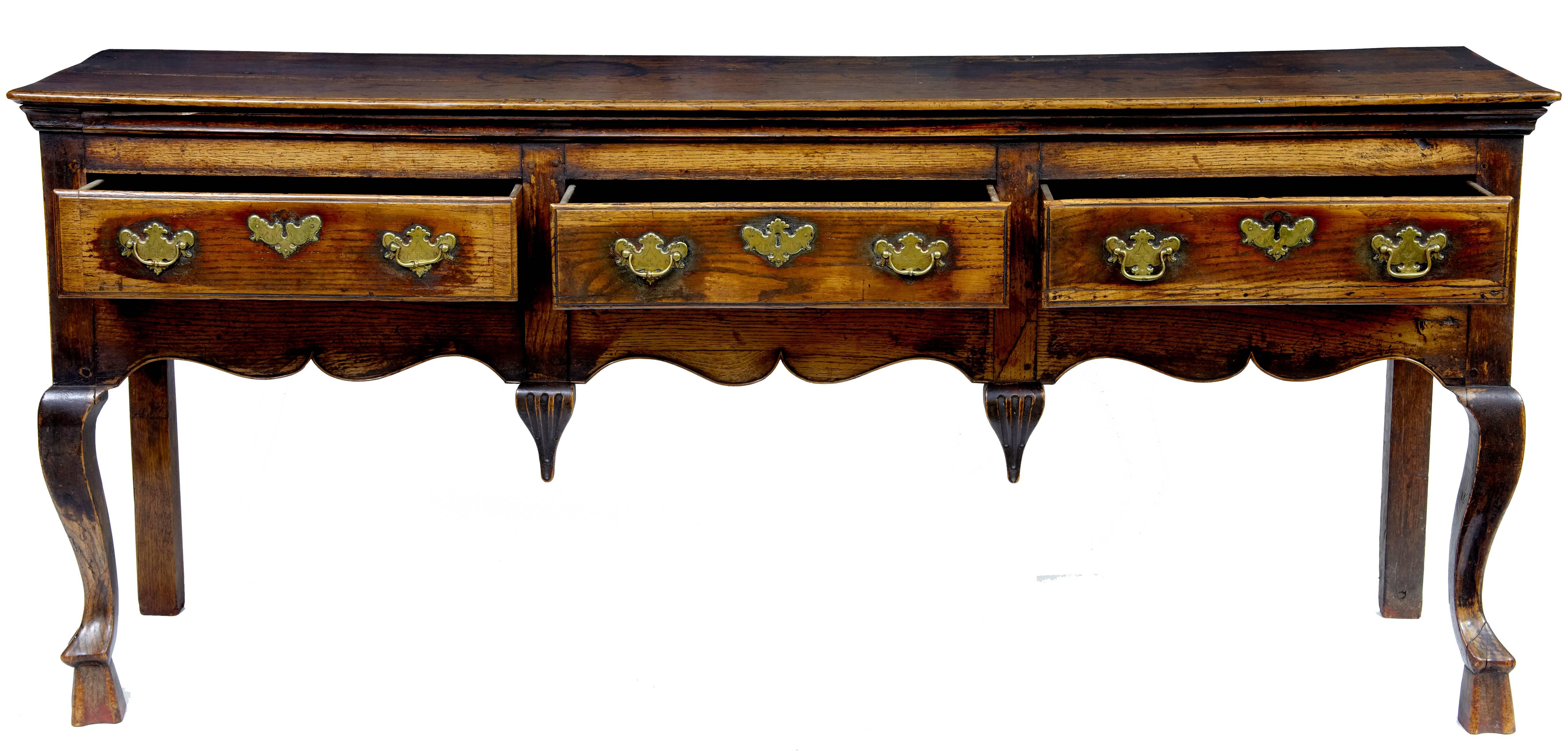 A superb quality early 18th century oak dresser, the moulded edge top above three oak lined drawers with original brass handles and escutcheons, a wonderfully shaped frieze decorated with inverted finials, supported on very rare and unusual cabriole