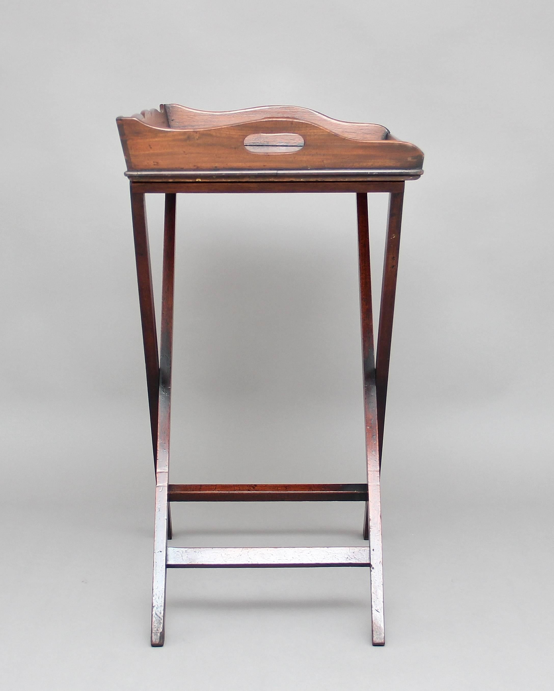 A lovely quality 19th century mahogany butlers tray on stand, the rectangular shaped tray with a surround gallery three quarters raised and with two fret cut carrying handles above a folding stand, circa 1830.