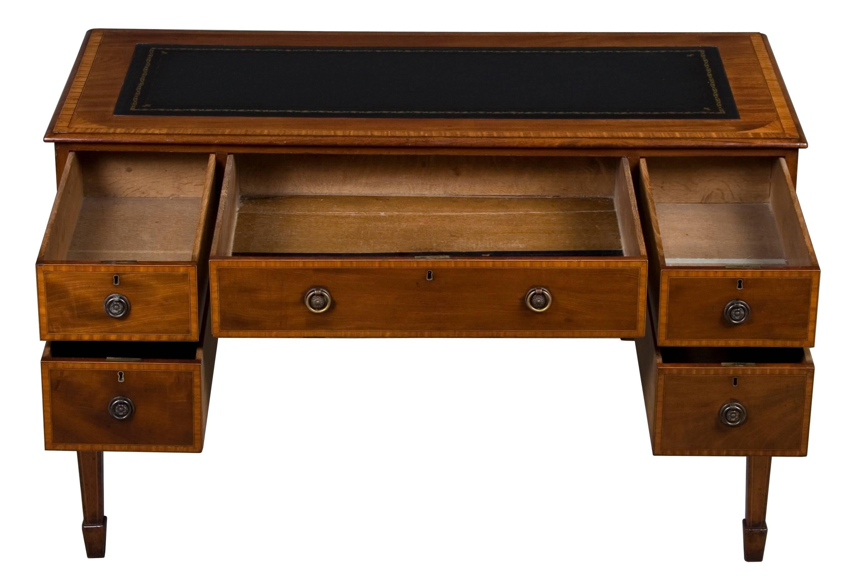 This English mahogany writing desk was made during the Edwardian period around the year 1910. It features five drawers that extend all the way to the back of the desk making the drawers quite large and spacious. As with many Edwardian pieces, the