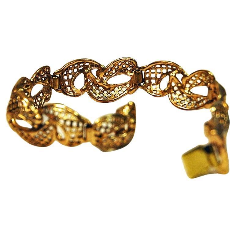 Brass bracelet sectioned together with six golden parts of perforated brass links shaped as eights. Lovely golden bracelet perfect for both everyday and party wear use. Box locker. Stamped: Made in Finland. 1970s. Measure: 20 cmL x 2 cmW x 0,1 cmD.