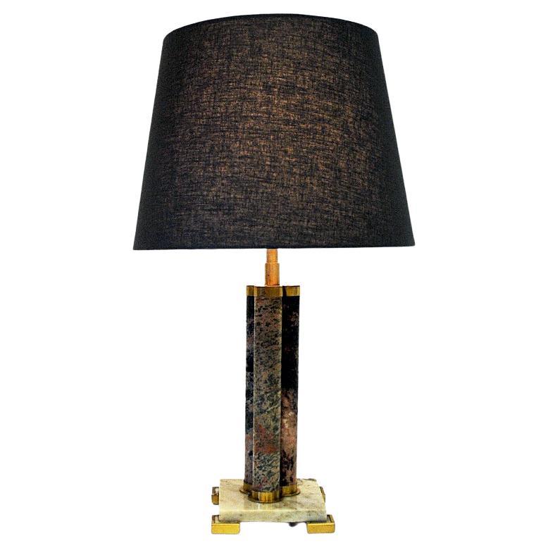 Decorative stone table lamp with a lovely mix of granite stone patterns on the sides. A colormix of brown, beige, red, grey and black gathered in three cylinder shaped poles with brass details on top and base. Marble stone base with brass feet.