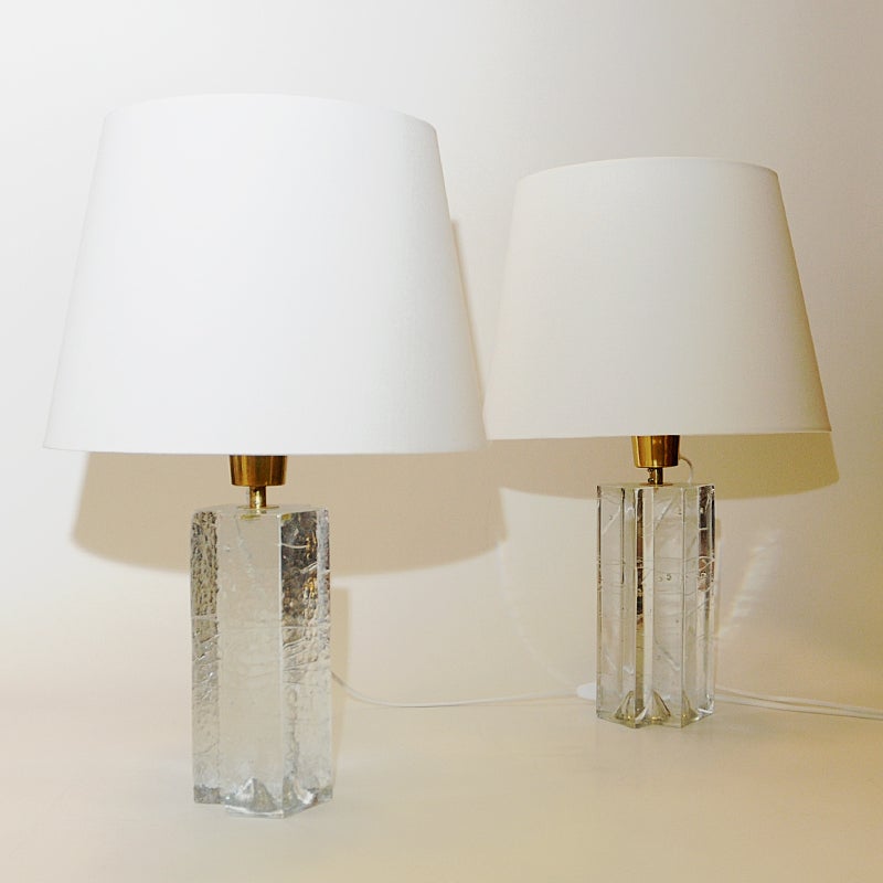 Magnificant pair of glass table lamps model `Arkipelago` designed by Timo Sarpaneva for Ittala, Finland in 1978. These heavy lamps are made of solid glass with air bubbles within and reminds of giant ice cubes. Brass bulb sockets. 
Irregular design