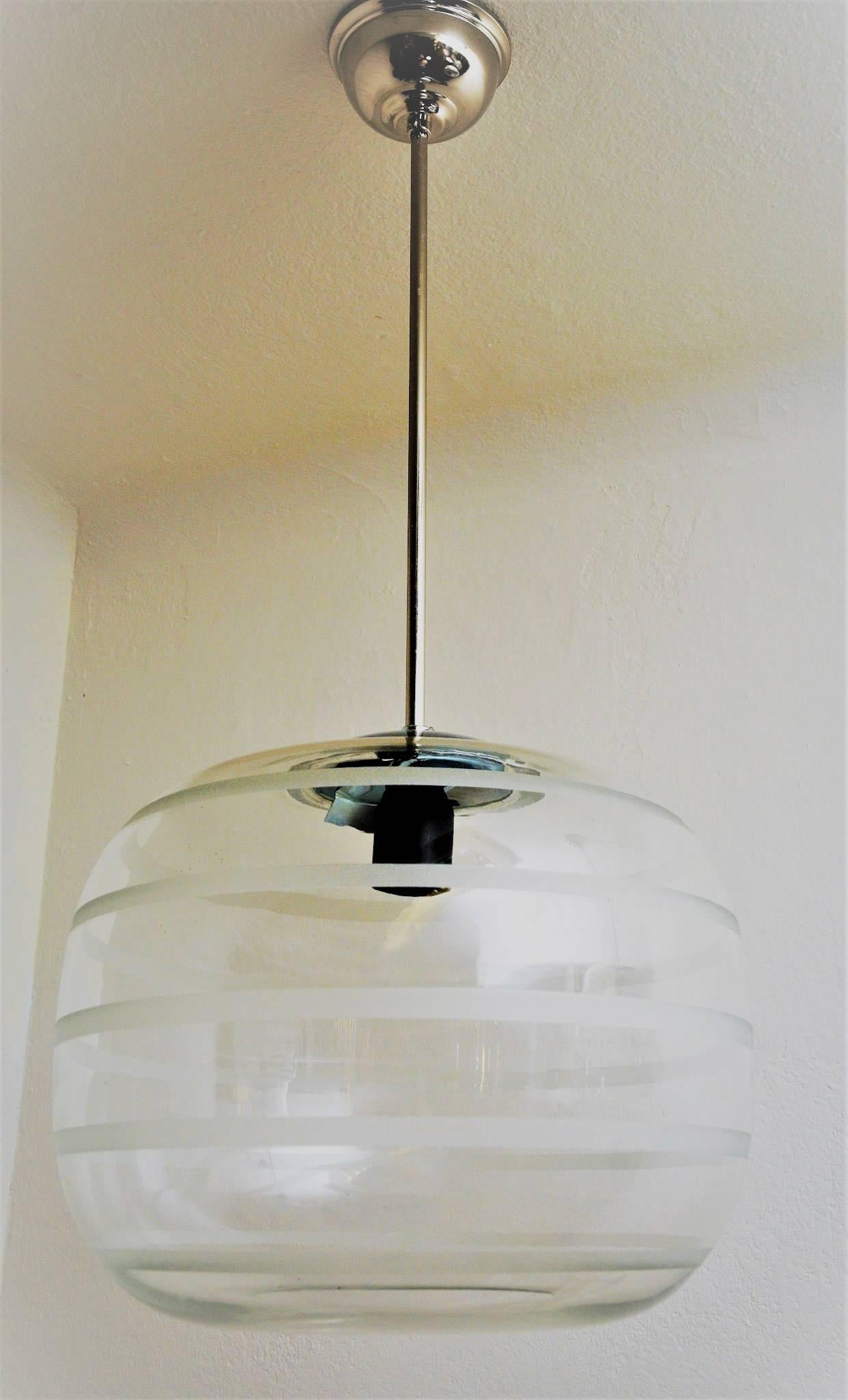 An oval classic vintage glass ceiling school lamp with a glassdome blown by mouth. The lamp has horizontal frosted stripes around. This midcentury lamp also have a new pendant and new electric equipment. These unique lamps has been hanging among