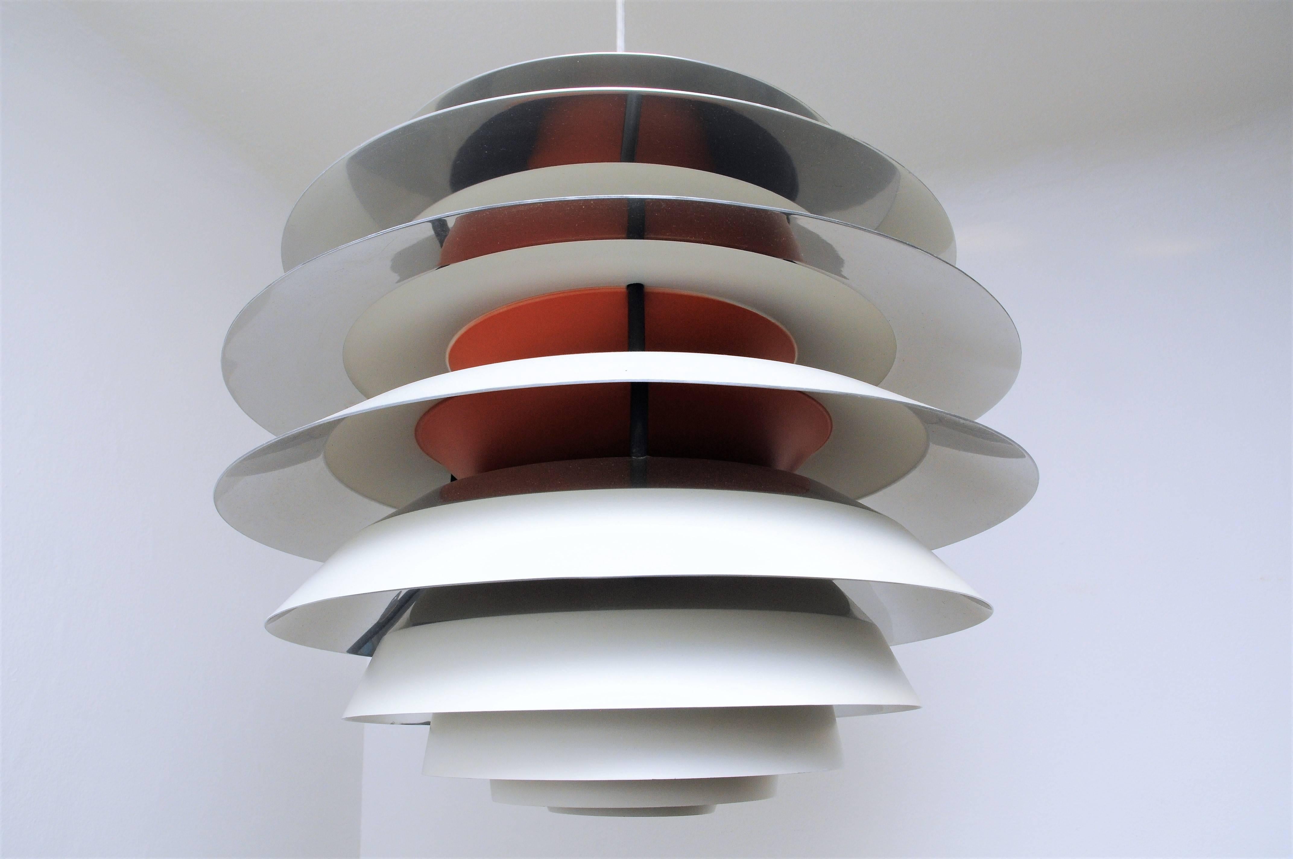 This model PH Kontrast pendant is composed of then shades. Each shade has four different surfaces which are painted in white, blue and red and one polished. The tubular core is adjustable in order to regulate contrast lighting. 
The piece was