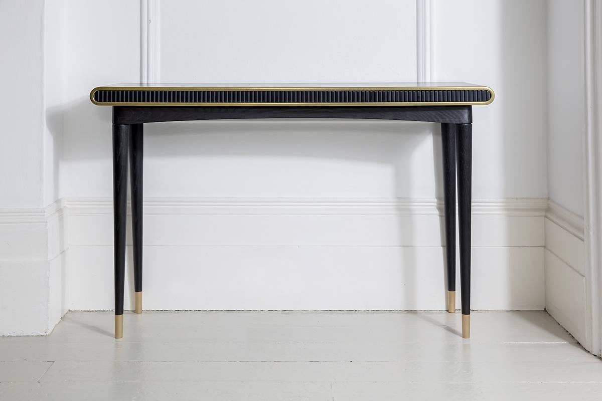 A distinctive console table that uses both liquid and solid brass, hand applied blackened oak, Corian, to create the perfect piece for any interior.

