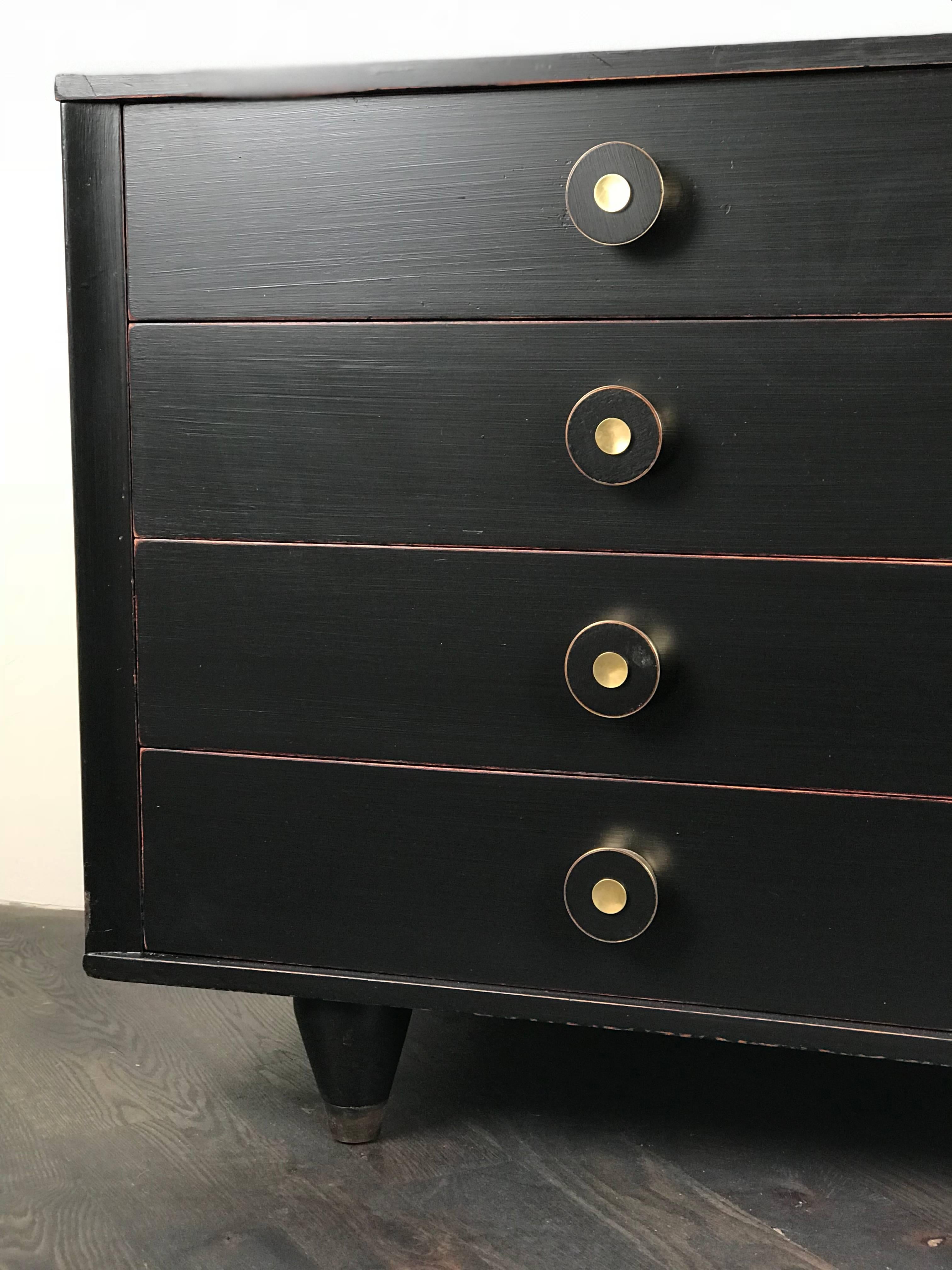 This Mid-Century Modern dresser features a dark painted finish, round brass pulls, cone-shaped legs and brass sabots, circa 1960.

