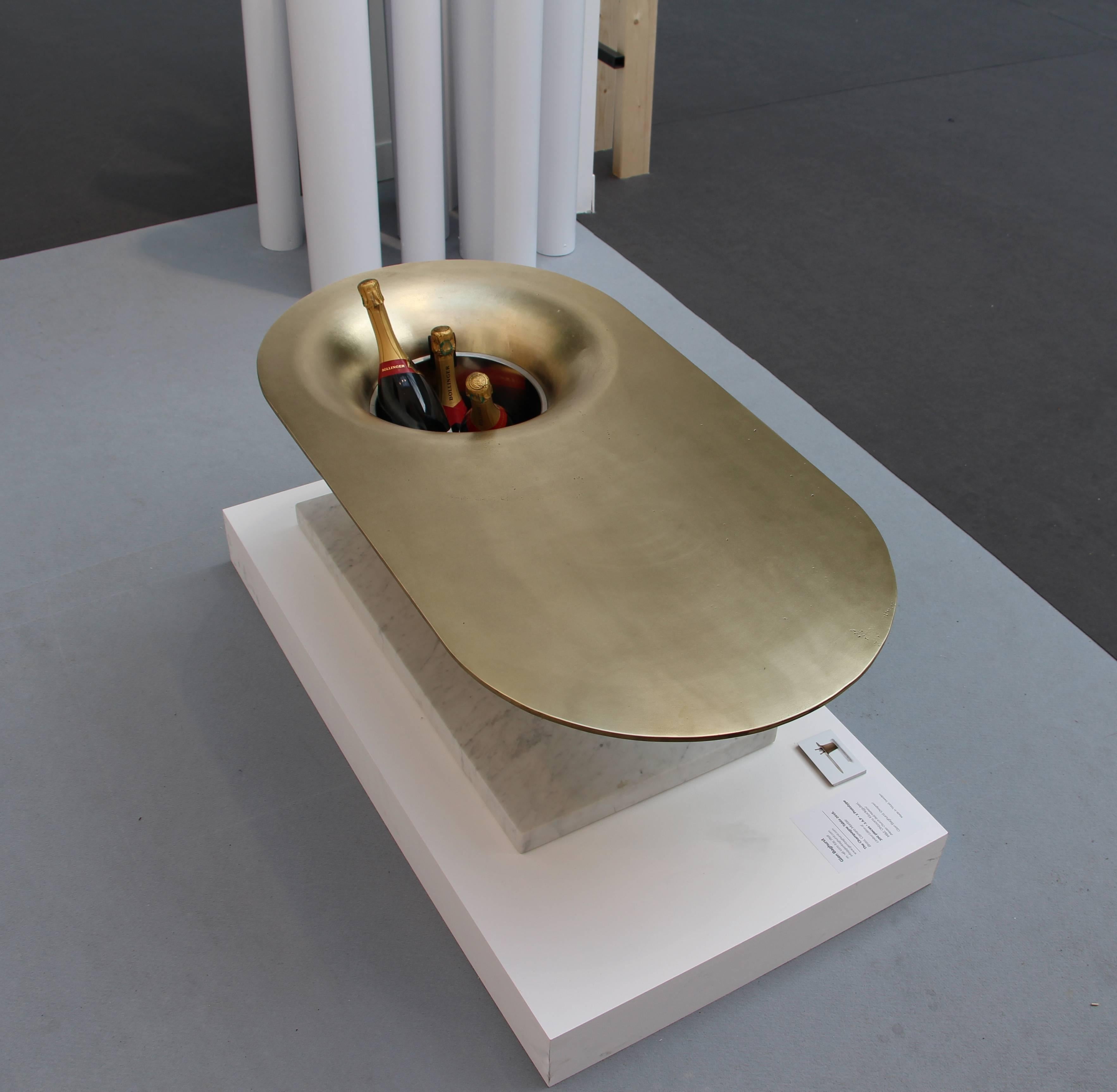 This heavy opulent table is used to chill and serve champagne. Three bottles of champagne should be kept in the bell at all times as potential for a great evening. The tabletop is made from solid cast brass. This is cantilevered by a heavy stone