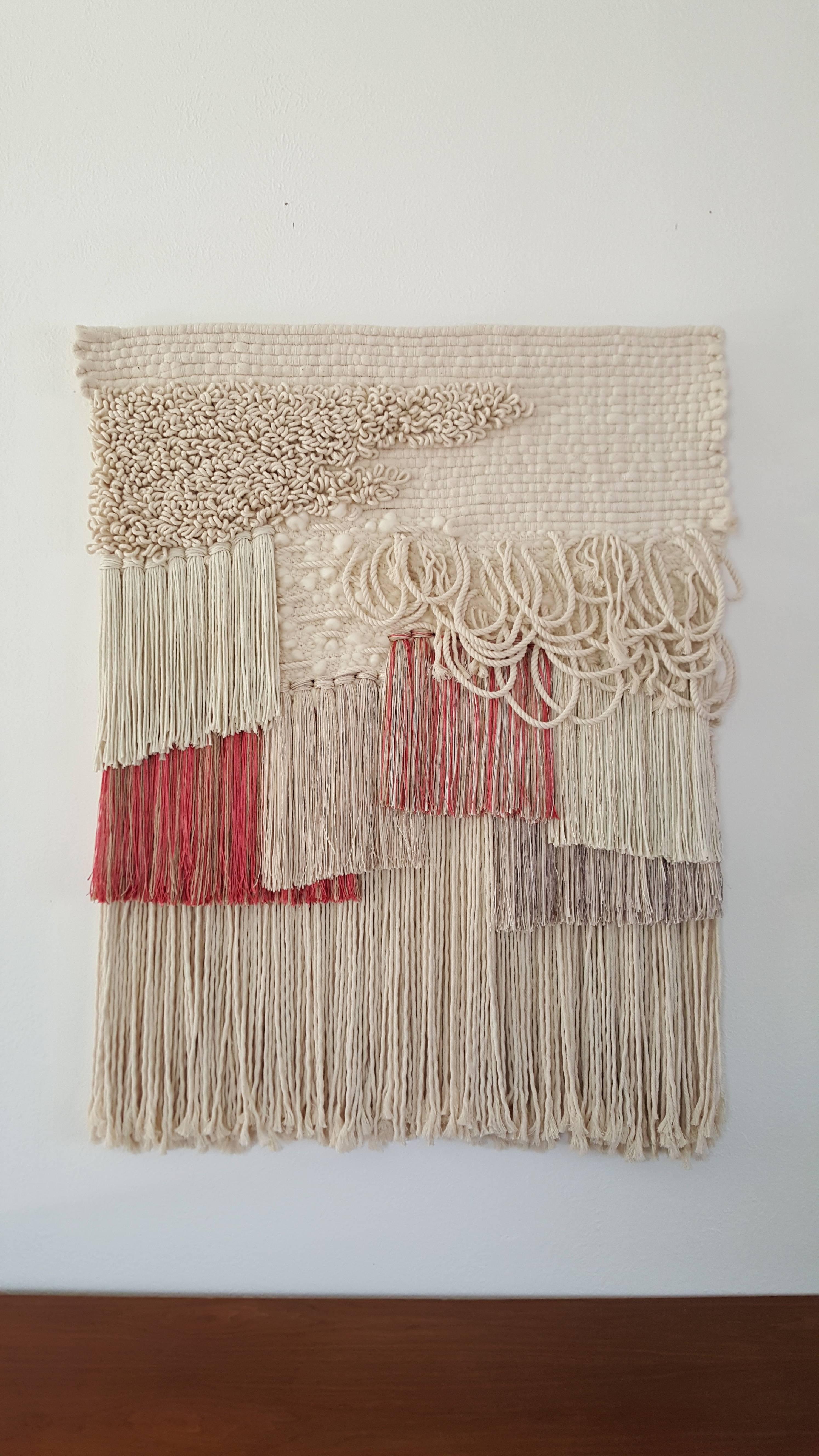 Hand woven, tapestry style, wall hanging by Janelle Pietrzak of All Roads.  Rich use of texture and color like creams and pink creates depth in this piece. Fibers used are cotton and shiny viscose.  Weaving hangs fully supported from a hidden french