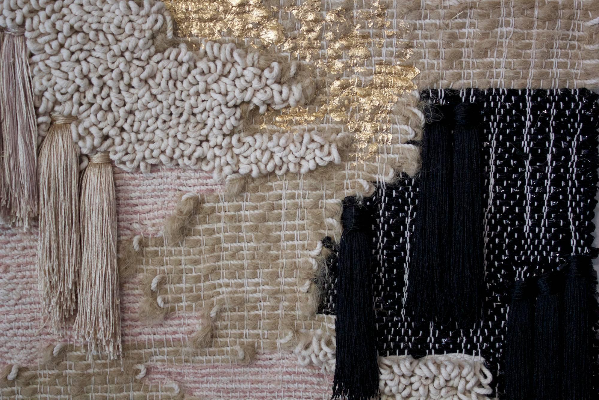 Handwoven, tapestry style, wall hanging by Janelle Pietrzak of All Roads. Pale pink yarns contrast with black. Shiny viscose tassels are drapey, and gold leafing is applied to rustic hemp fiber. Weaving hangs from a solid steel rod. 

This textile