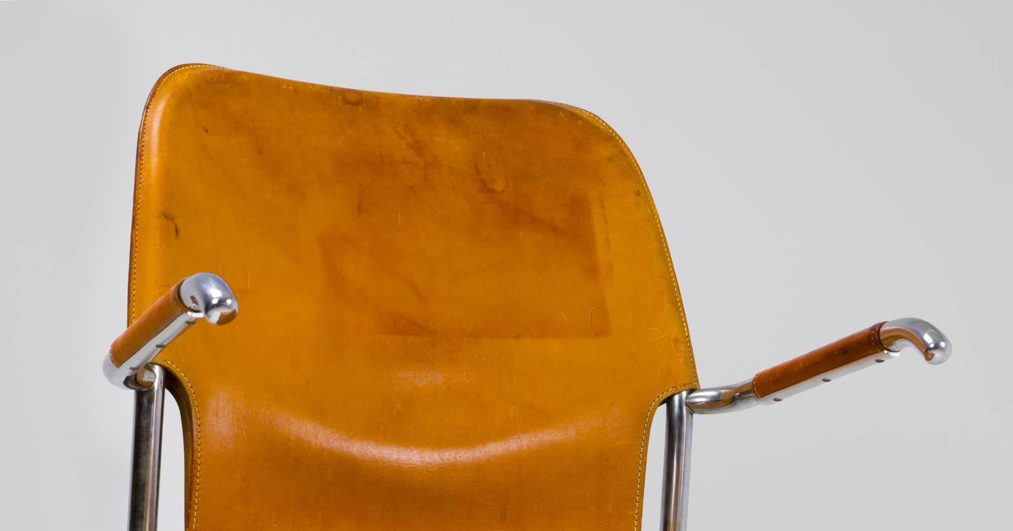 Tubular steel cantilevered armchair by Kenneth Bergenblad for DUX with well-weathered cognac leather stretched around a minimal frame, with leather wrapped single tube arm rests.