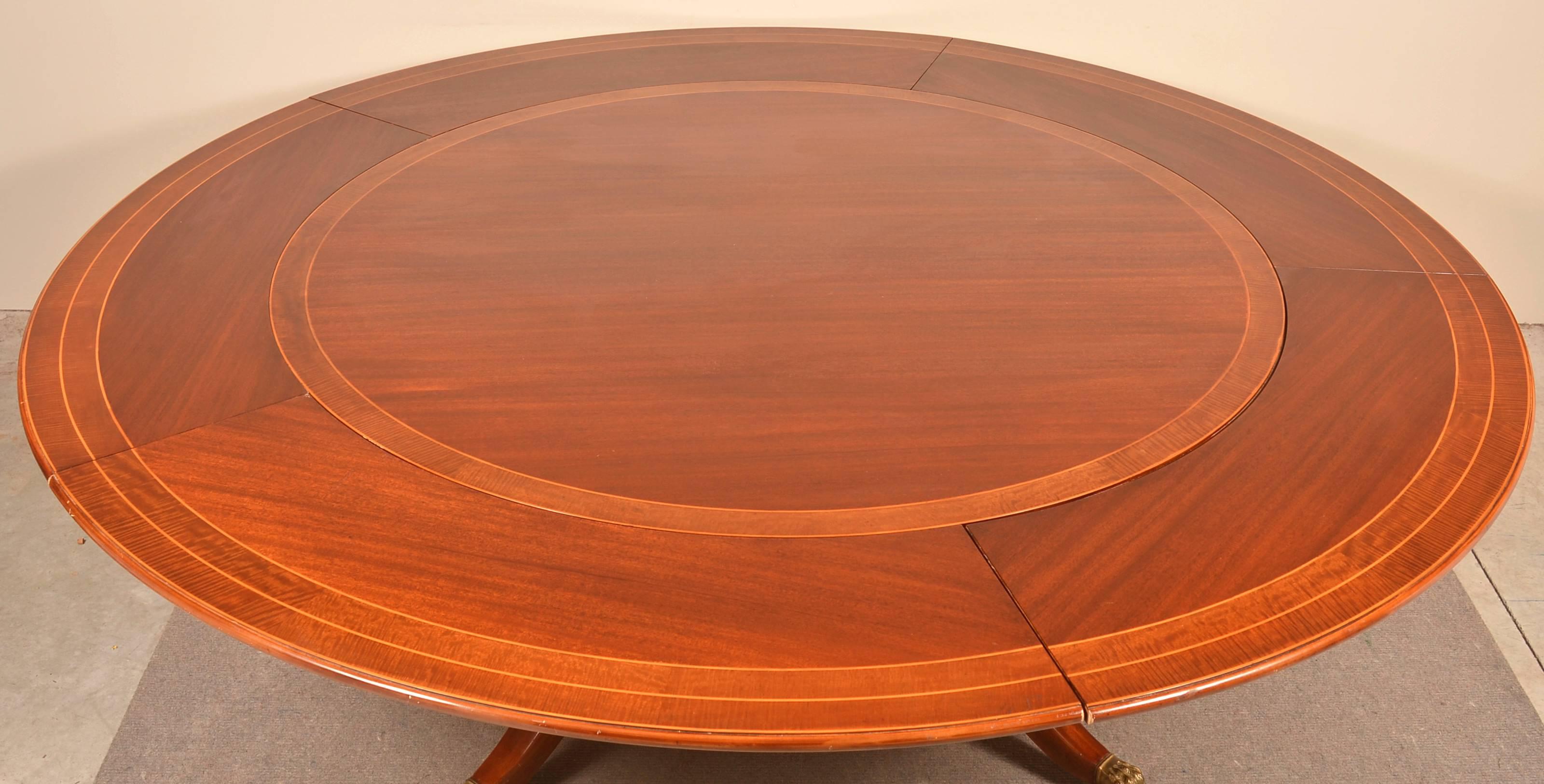 Mahogany federal style circular top dining table. Top with banded inlay, turned supports, shaped legs with brass capped paw feet. Accompanied with the original 14