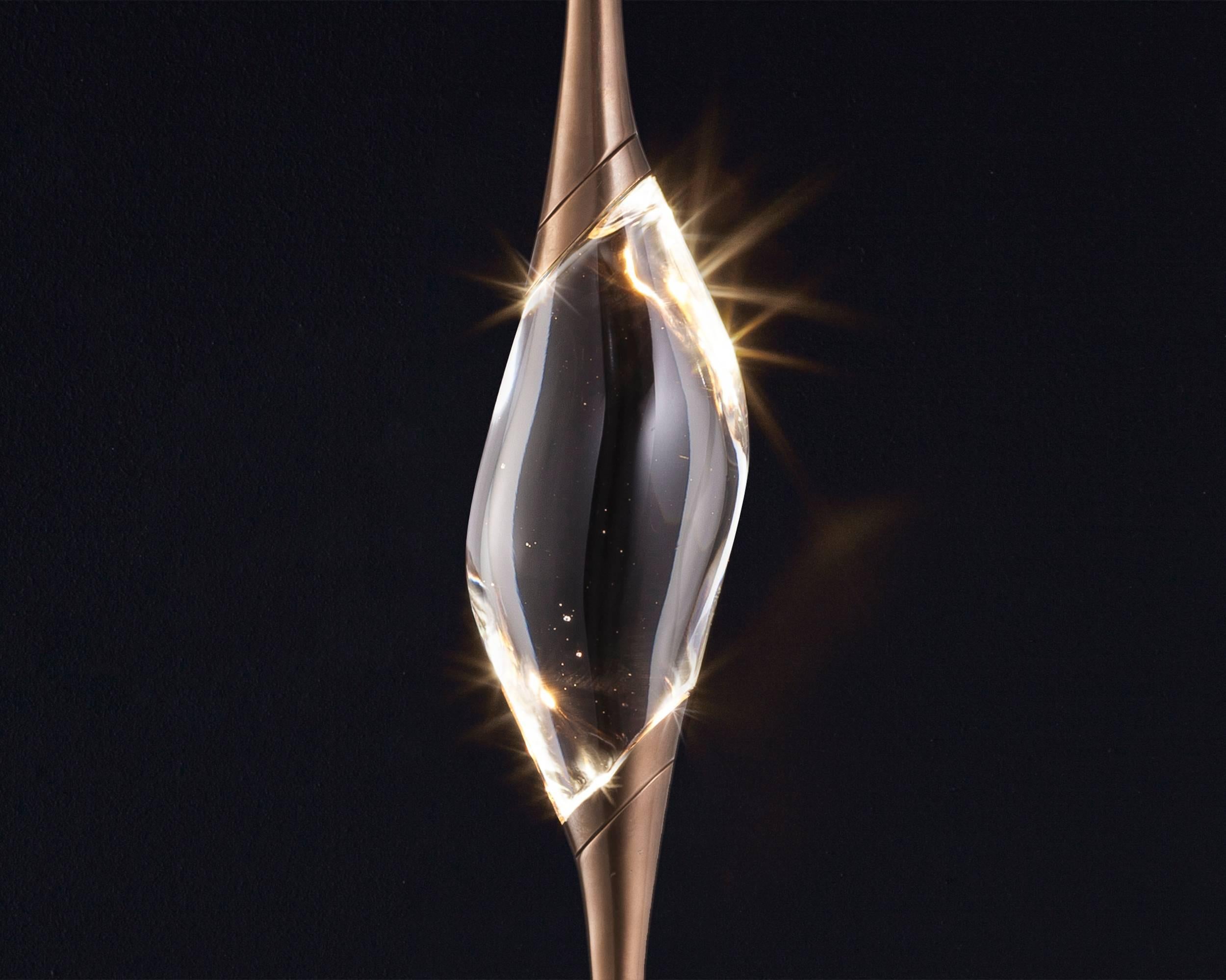 Il Pezzo 12 is a female figure suspended in the air, carrying in her womb the light. It’s nimble, refined, addictive. The solid crystal, illuminated by LEDs, creates suggestive refractions and it’s suspended between brass stems finished in