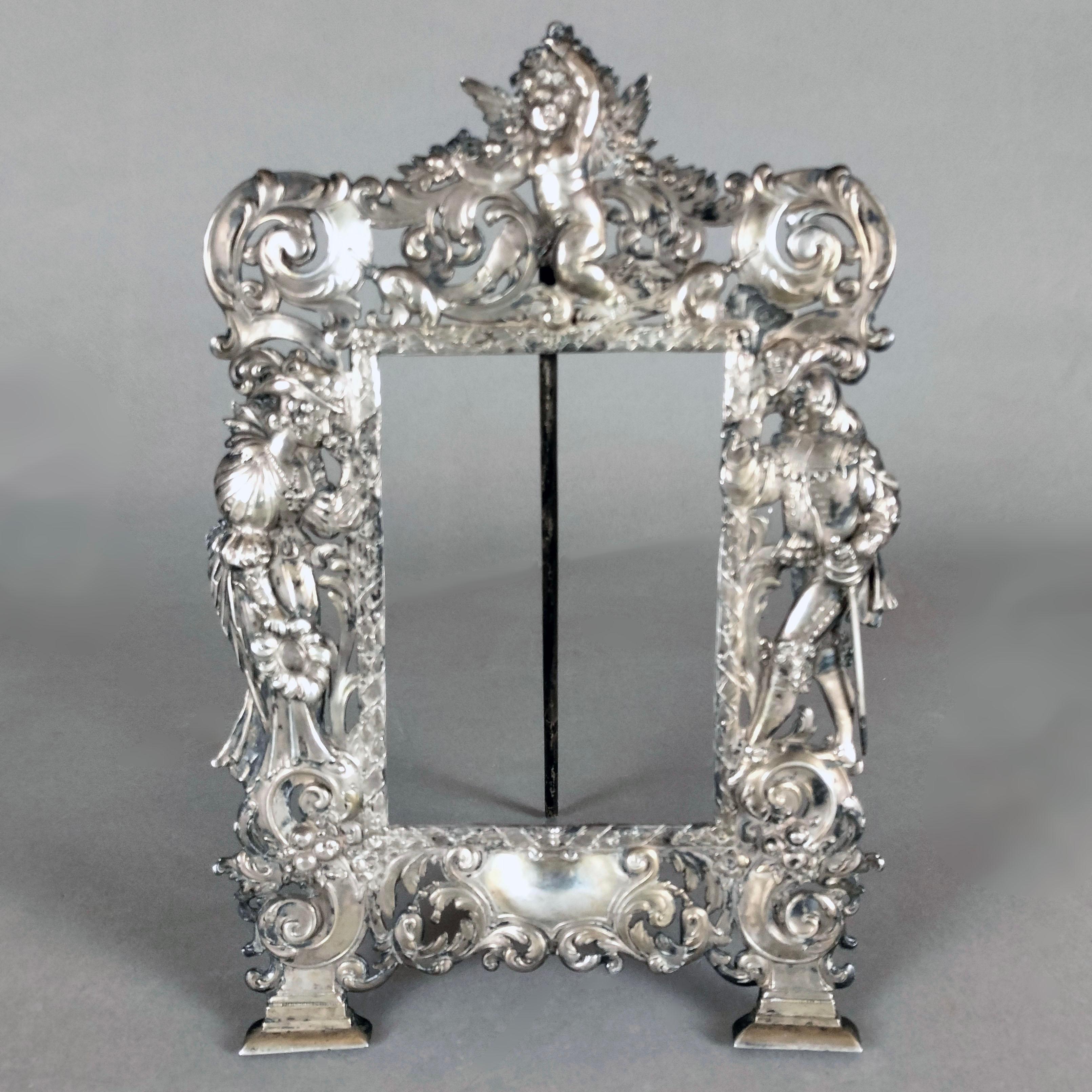 A rare ca. 1895 Hanau, Germany .810 silver picture frame by B. Neresheimer & Sohne. The upper section shows a putti carrying a festoon with flowers. The whole frame is decorated with vegetal scrolls and acanthus leaves. On the sides, we can see a