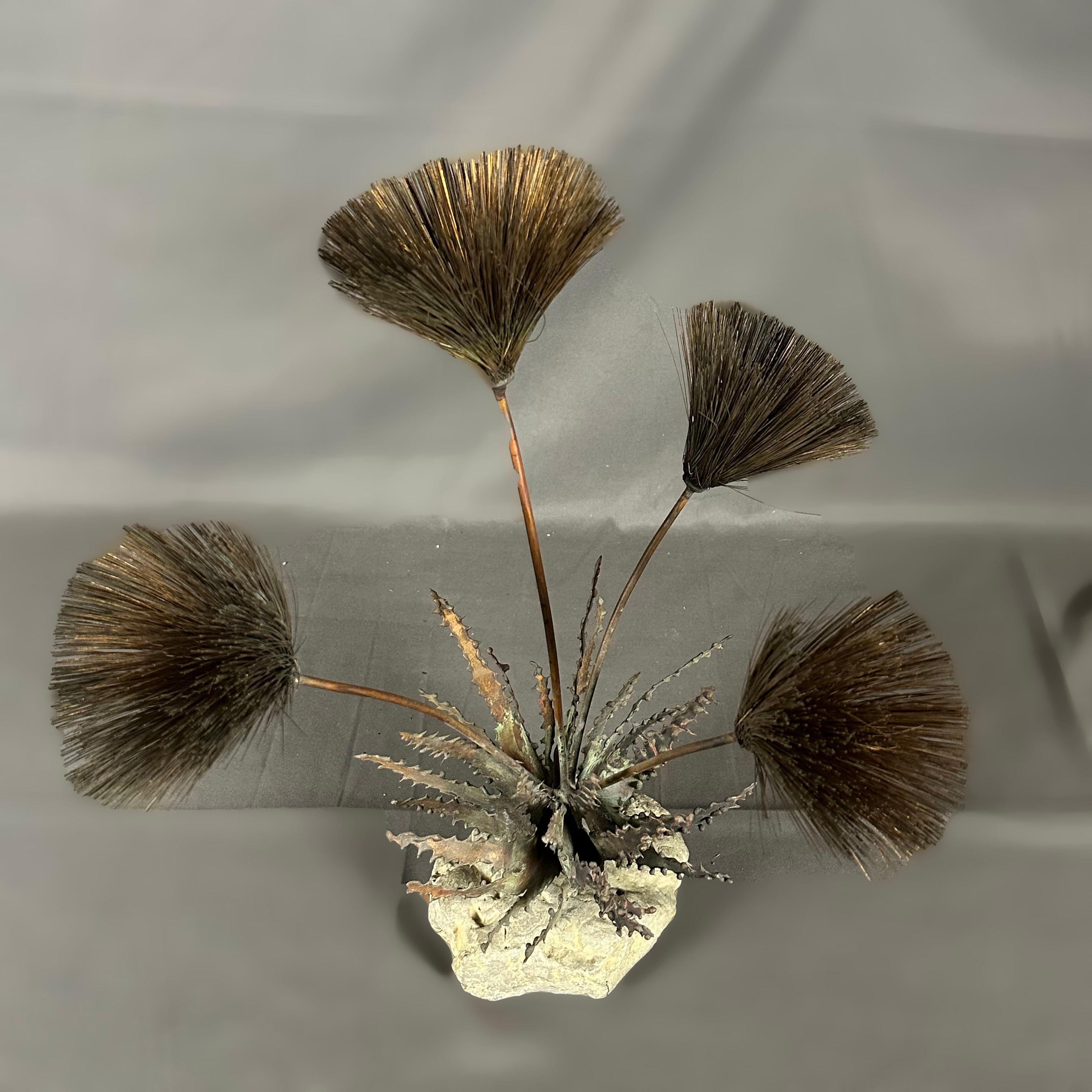 A 1960's Brutalist copper, steel and stone sculpture by John Steck. The steel stems hold 4 dandelion-shaped flowers in copper wire and the leaves surrounding them. The sculpture is fixed on a stone base. All metal pieces show the patina of time.

A