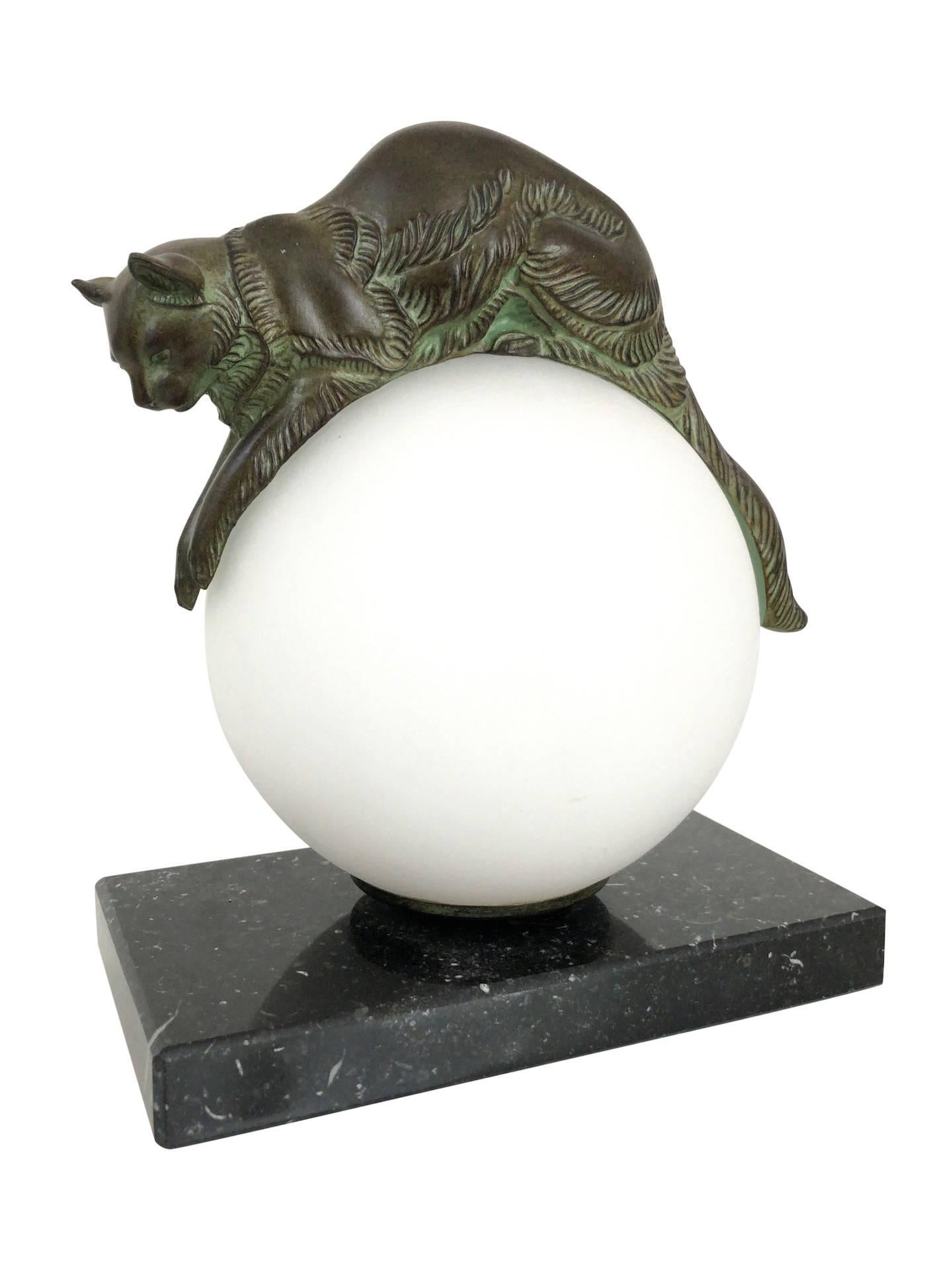 “Equilibre” 
Cat keeps balance on a lighted glass ball 
Designed in France during the roaring 1920s by “Gaillard” 
Original “Max Le Verrier” 
Art Deco style, France.

Table lamp made in “Régule” (spelter)
Socle in black marble (could have a