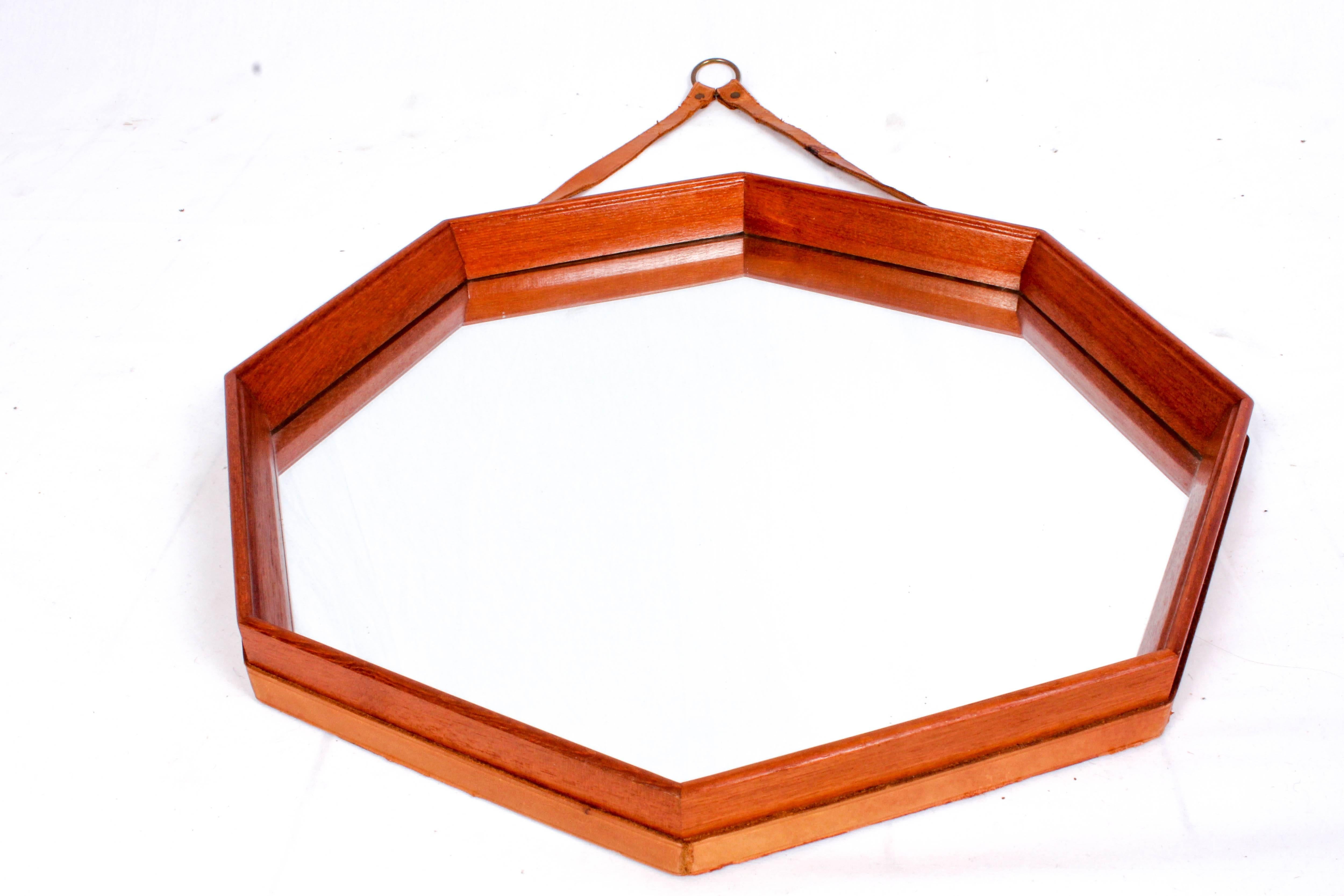 Midcentury Swedish octagonal teak mirror with original leather strap. This is a rare and very decorative mirror with a nicely cut edge. The mirror is in excellent vintage condition but the leather strap has signs of usage and repairs.

This item