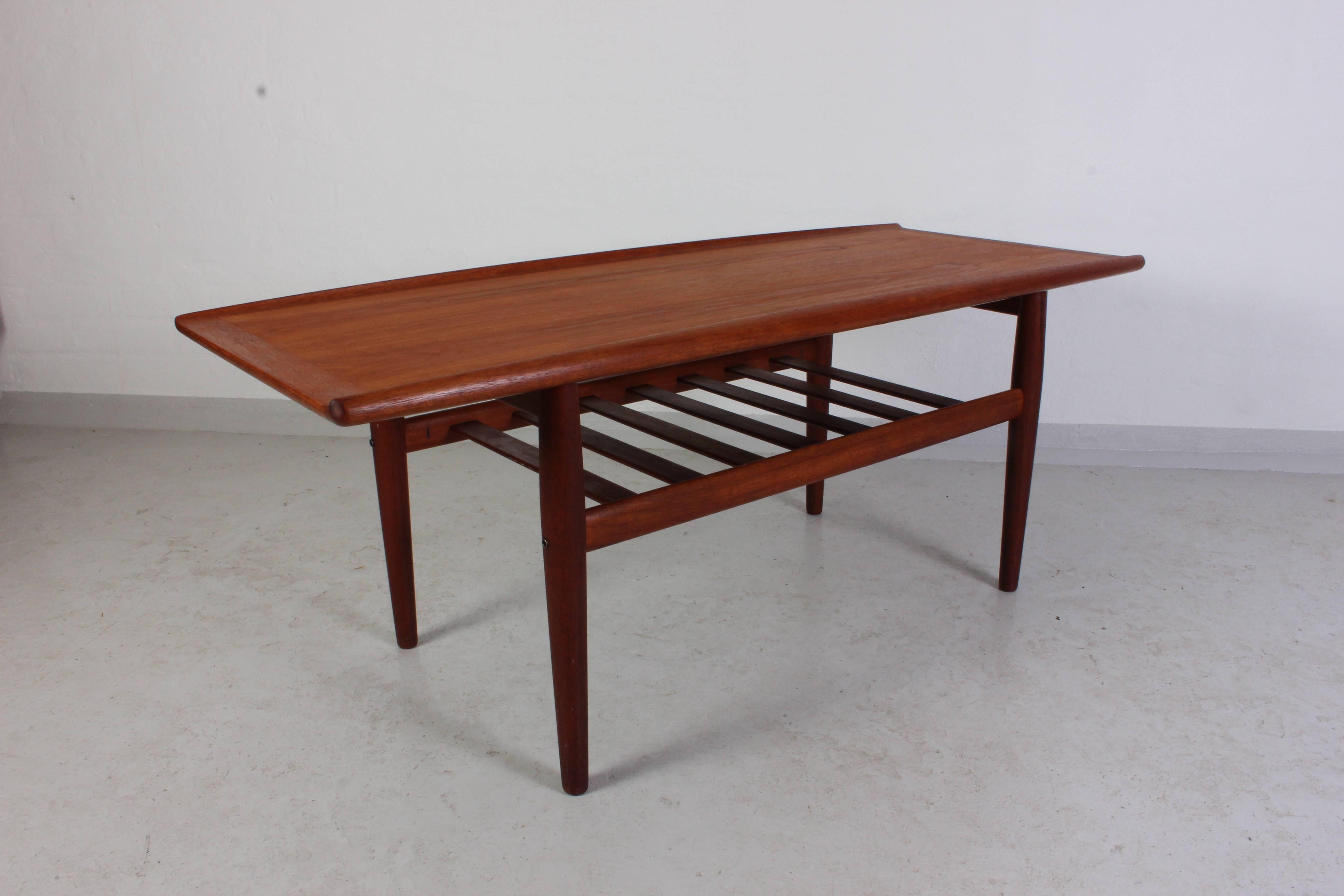 Midcentury teak coffee table by Danish designer Grete Jalk produced by manufacturer Glostrup. The table is made out of solid teak and the shelf underneath the top is mounted with brass fittings. This high quality coffee table is in very good vintage