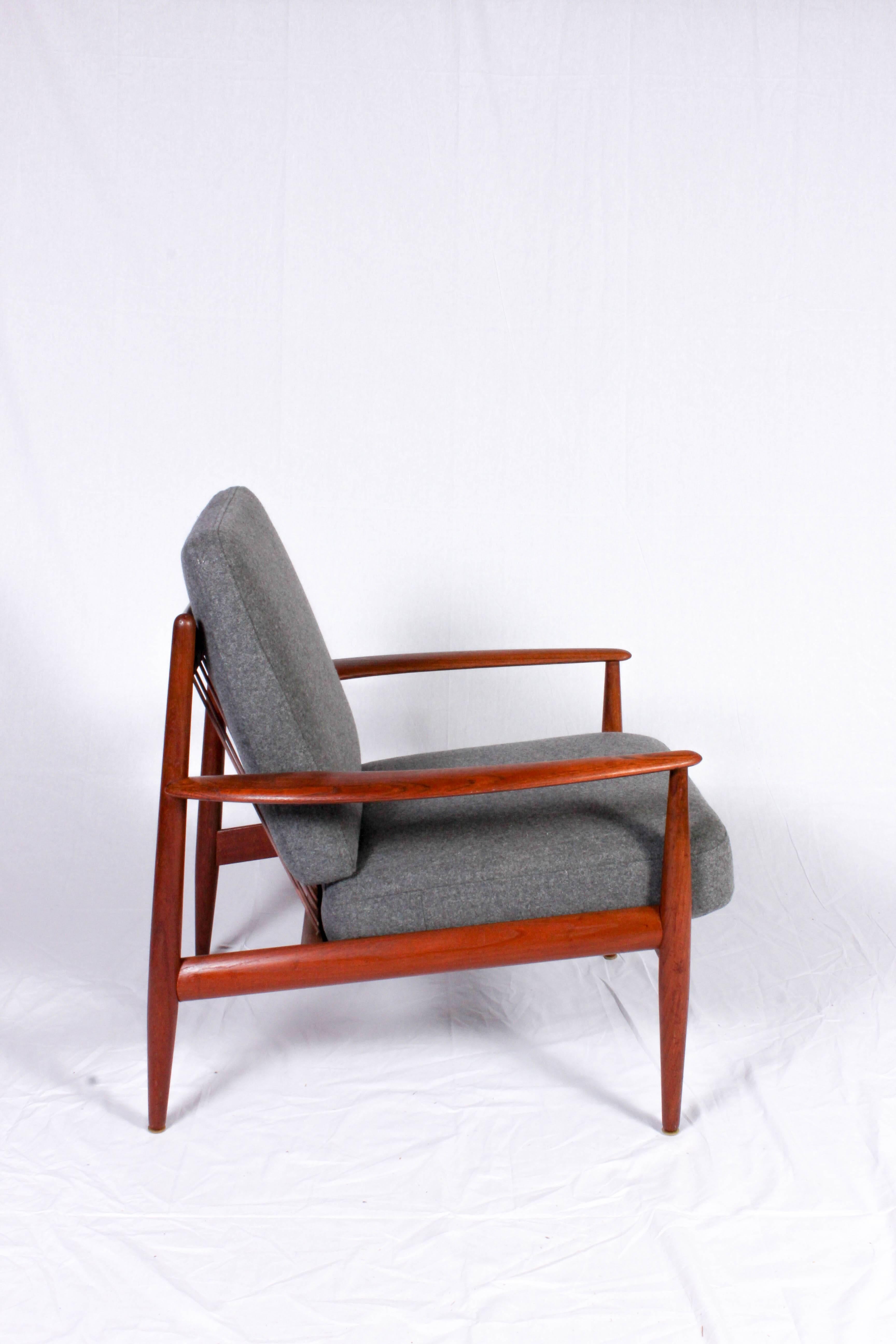 Midcentury Danish solid teak lounge chair by designer Grete Jalk for Glostrup Møbler. The chair is made out of a teak frame with cushions that has been reupholstered in a grey 100% wool fabric of high quality. 

The chair is in excellent vintage