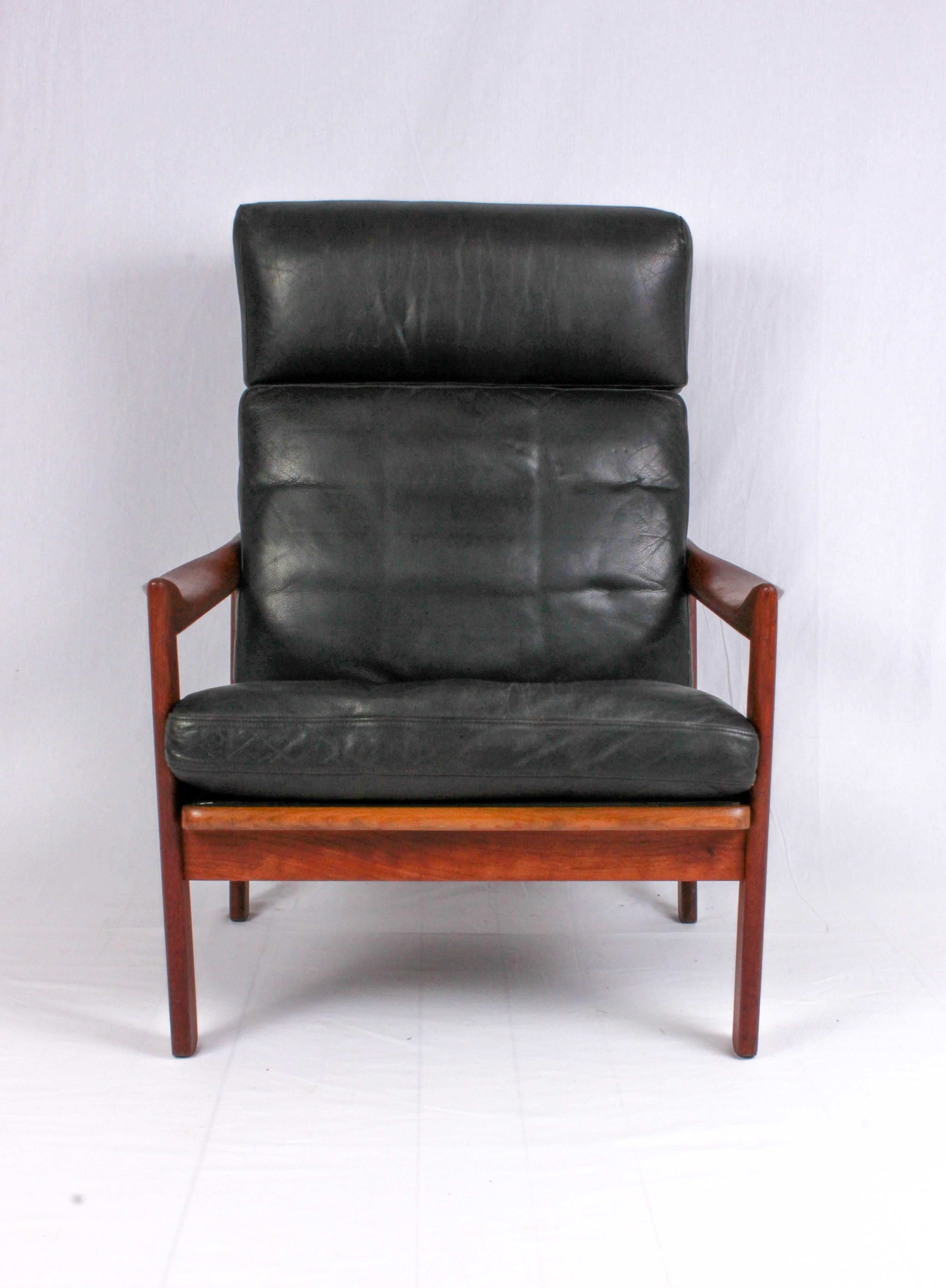 This midcentury teak high-back armchair is designed by Danish designer Illum Wikkelsø and produced by Niels Eilersen. The chair has beautiful twisted armrests and original leather upholstery with minor signs of usage and patina. A very decorative