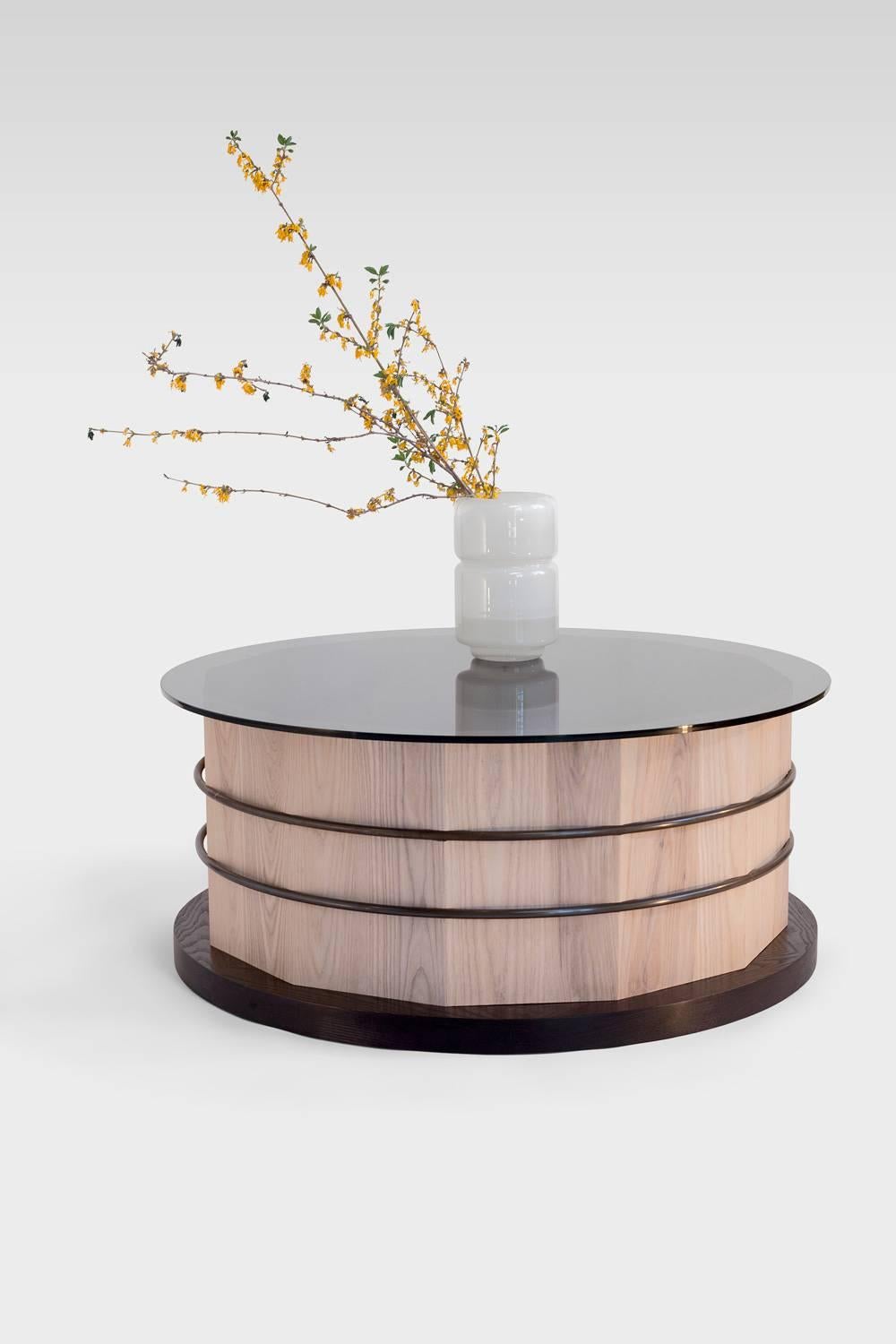 The table is highly customizable. Shown here is whitewashed ash with a salmon dyed base, pink powder-coated steel hoops and a smoked glass top. 

This unique contemporary table has floating steel hoops let into a 12-sided stave base, and hold up a