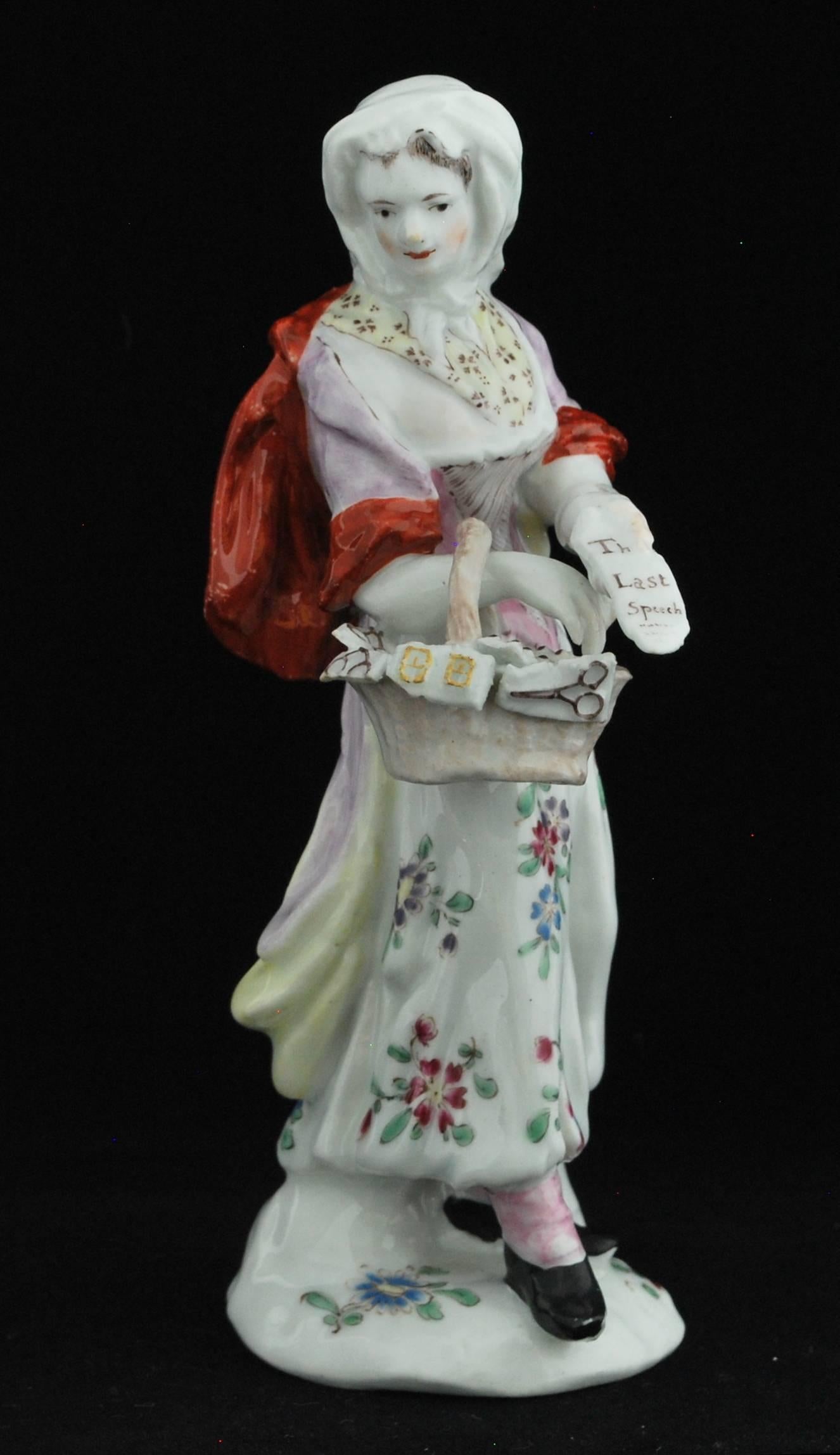 On a mound base decorated with painted floral sprigs. She wears a pale pink-mauve washed shift with iron-red sleeves and cloak, pale mauve and pink stomacher and a sprigged white shirt, a tied head scarf and patterned neck scarf and pink stockings