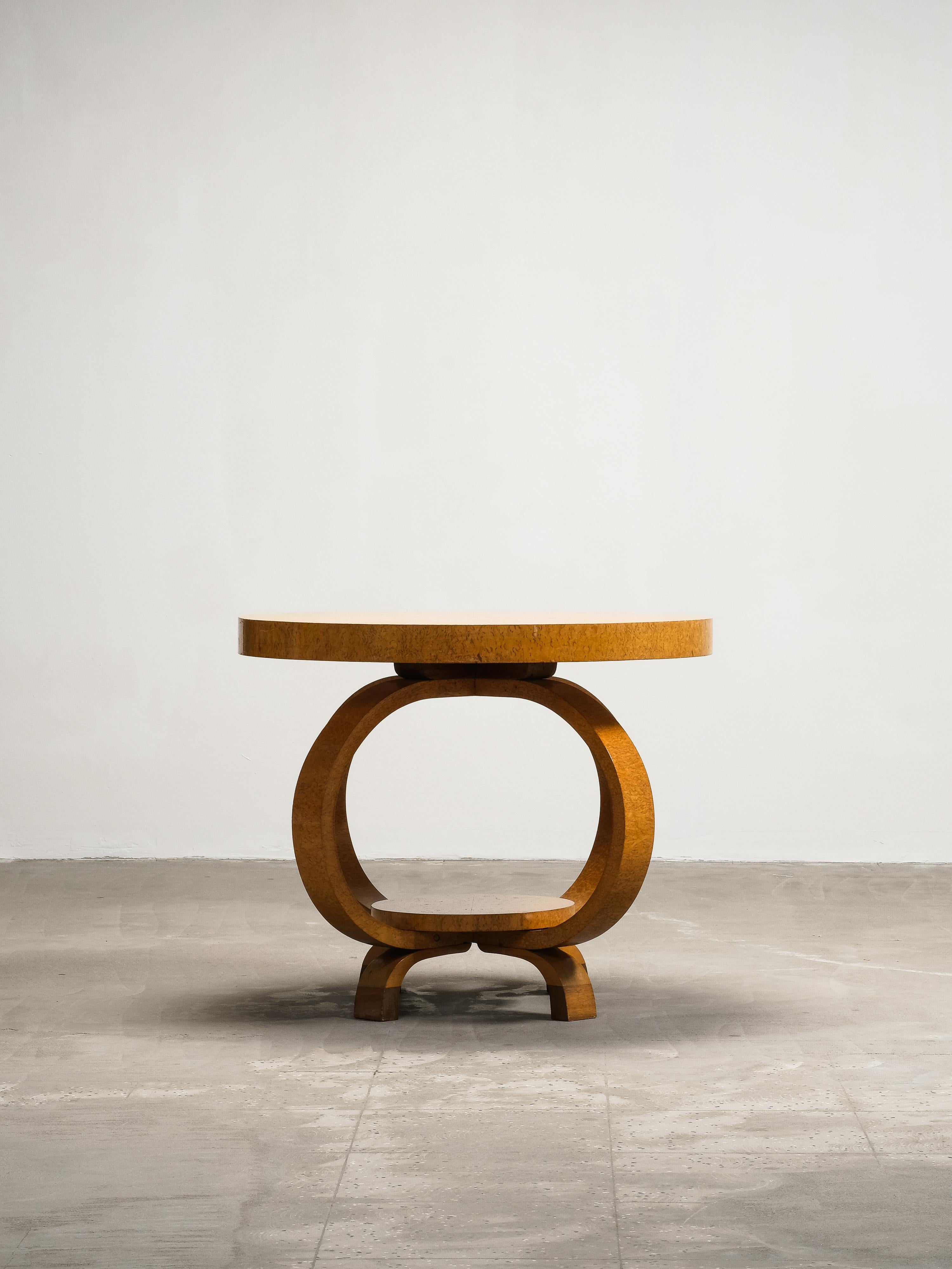 A sculptural Finnish Art Deco coffee table from the 1930s, featuring a striking round top in richly figured burlwood. This elegant piece exemplifies the craftsmanship and geometric refinement characteristic of Scandinavian Art Deco design, combining