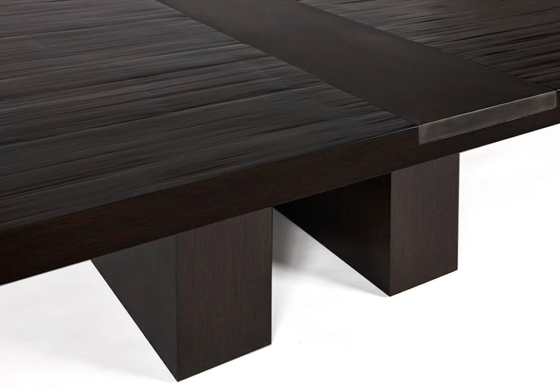 Simple yet sophisticated, a blackened steel insert adds industrial edge to the organic texture of this modern bamboo-top dining table. The surface is mounted on two rift-oak plinths, giving it an elegant look that also leaves plenty of legroom for