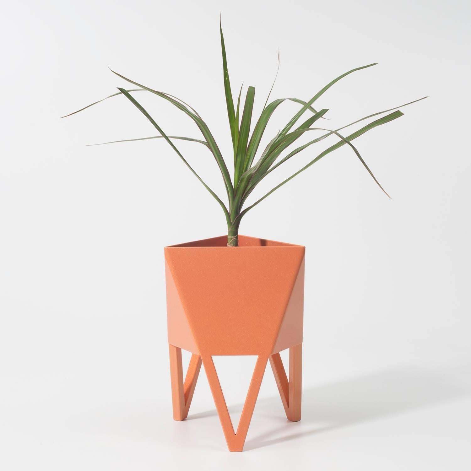 Introducing Force/Collide's signature planter in sunbeam salmon pink. Using a seamless brake-forming technique, one sheet of steel is wrapped into a unique geometric pattern that's triangular at the top and hexagonal at the base. Three V-shaped legs