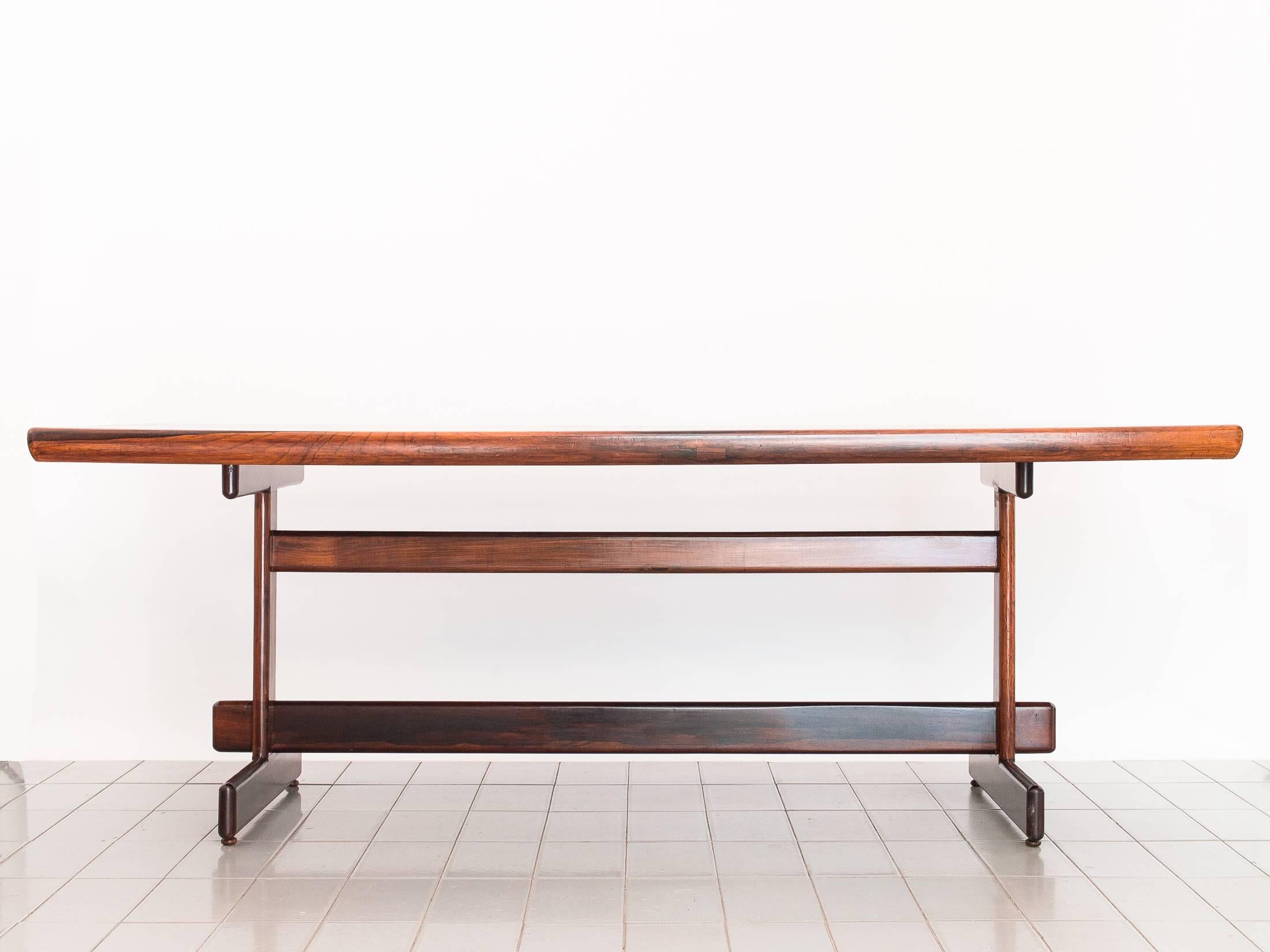 Beautiful rosewood dining table, designed by Sergio Rodrigues in the early 1960s. Feet, legs and stretcher are solid rosewood, top is veneered with solid beveled edges. Fully restored and refinished. Fits eight chairs comfortably.