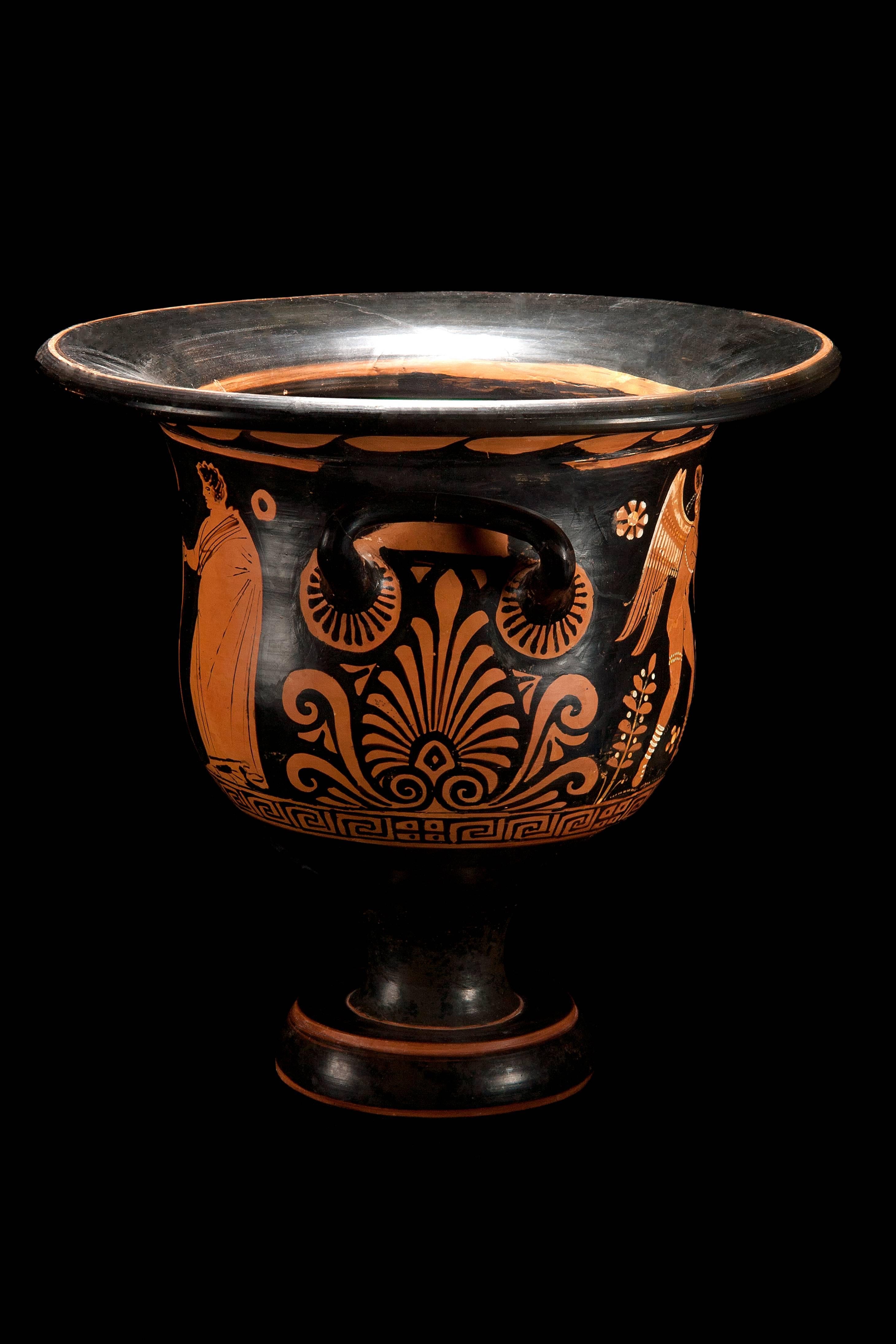 A very nice and lovely example, red-figure painted, pottery wine mixing bowl, standing on a graceful pedestal foot which supports the bell shaped body with two opposing handles beneath the flared, wide rim. The main scene shows a standing, nude,