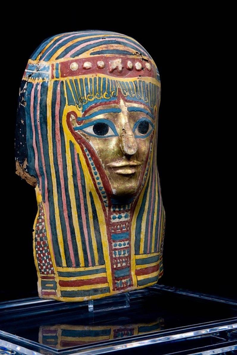 Masque de momie au teint doré. Il porte une perruque tripartite striée retenue par un bandeau noué et décorée sur le devant d'un oudjat (œil d'horus) et de globules (cercles) ; un collier ousekh est peint entre les côtés. Les sourcils et les yeux